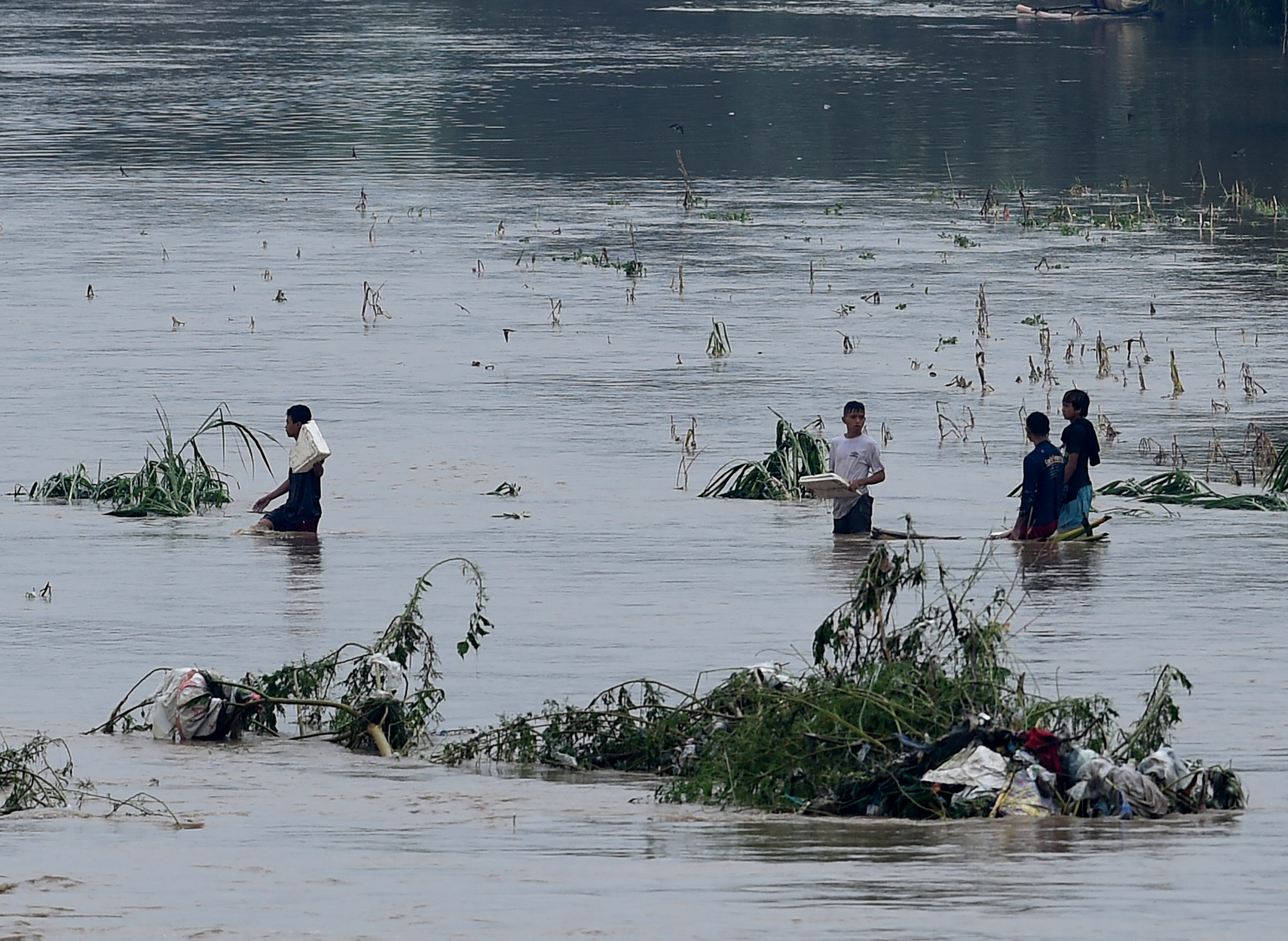 Residents try to cross a river after it flooded an area in San Mateo, Rizal province, east of Manila on August 14, 2016. Heavy downpours overnight caused flooding to houses near the riverbank, brought about by a southwest monsoon. / AFP PHOTO / TED ALJIBE
