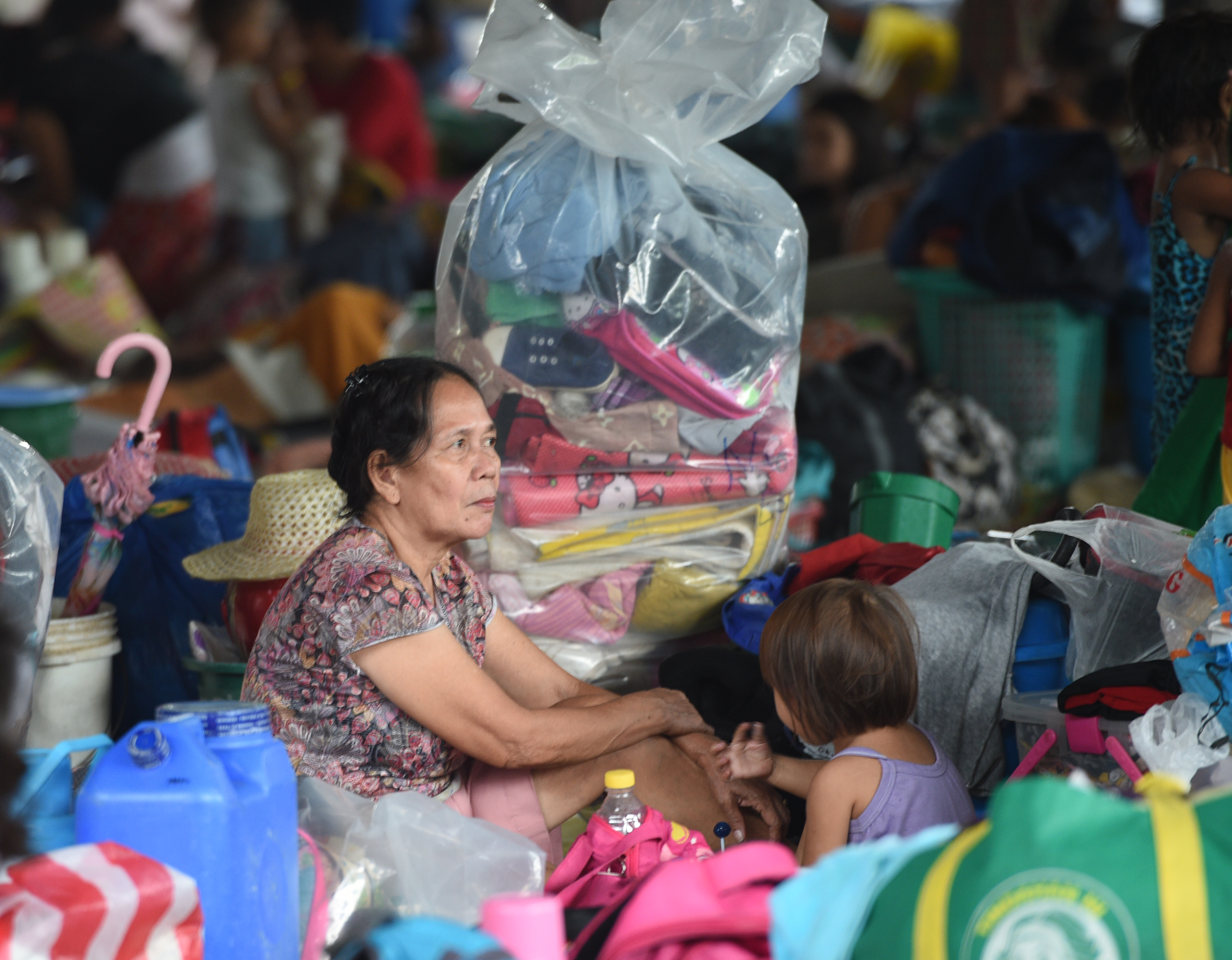 Residents rest inside a covered basketball court used as temporary shelter for residents affected by flooding in San Mateo, Rizal province, east of Manila on August 14, 2016. Heavy downpours overnight caused flooding to houses near the riverbank, brought about by a southwest monsoon. / AFP PHOTO / TED ALJIBE