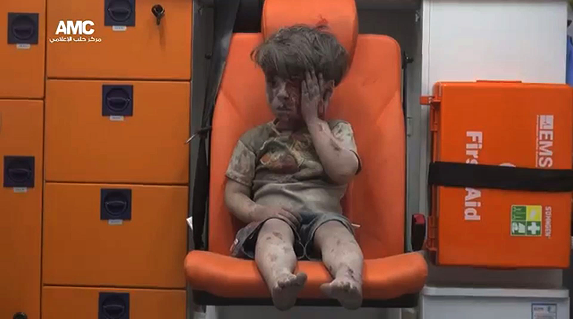 An image grab taken from a video uploaded by the Syrian opposition's activist group Aleppo Media Centre (AMC) on August 17, 2016 is said to show a young Syrian boy covered in dust and blood touching a wound on his head as he sits in shock in an ambulance after being rescued from the rubble of a building hit by an air strike in the rebel-held Qaterji neighbourhood of the northern Syrian city of Aleppo. / AFP PHOTO / AMC / HO / === RESTRICTED TO EDITORIAL USE - MANDATORY CREDIT "AFP PHOTO / HO / AMC " - NO MARKETING NO ADVERTISING CAMPAIGNS - DISTRIBUTED AS A SERVICE TO CLIENTS FROM ALTERNATIVE SOURCES, AFP IS NOT RESPONSIBLE FOR ANY DIGITAL ALTERATIONS TO THE PICTURE'S EDITORIAL CONTENT, DATE AND LOCATION WHICH CANNOT BE INDEPENDENTLY VERIFIED ===   /