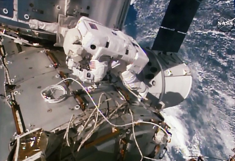 This NASA TV video grab shows US astronaut Kate Rubins working outside the International Space Station with the SpaceX Dragon space freighter just below her on August 19, 2016. With more private spaceship traffic expected at the International Space Station in the coming years, two US astronauts embarked on a spacewalk Friday to install a special parking spot for them. The spacewalk began at 8:04 (1204 GMT) when Americans Jeff Williams and Kate Rubins switched their spacesuits to internal battery power. Shortly afterward, they made their way outside the orbiting laboratory to begin the work of attaching an international docking adaptor, launched aboard a SpaceX Dragon cargo ship last month. / AFP PHOTO / NASA TV / HO / RESTRICTED TO EDITORIAL USE - MANDATORY CREDIT "AFP PHOTO / NASA TV" - NO MARKETING NO ADVERTISING CAMPAIGNS - DISTRIBUTED AS A SERVICE TO CLIENTS