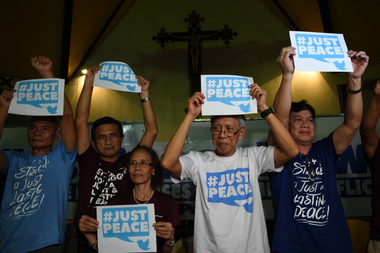 This photo taken on August 18, 2016 shows first batch of freed communist lebel leaders led by Alan Jasminez (2nd L) display placards during a press conference in Manila. Philippine communist guerrillas will observe a seven-day truce from August 21 to bolster upcoming peace talks hosted by Norway, the rebels said, urging the Manila government to also order a ceasefire. / AFP PHOTO / TED ALJIBE