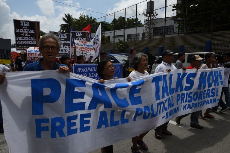 This photo taken on August 19, 2016 shows activists carrying a streamer march towards the police headquarters for a rally in Manila. Philippine communist guerrillas will observe a seven-day truce from August 21 to bolster upcoming peace talks hosted by Norway, the rebels said, urging the Manila government to also order a ceasefire. / AFP PHOTO / TED ALJIBE
