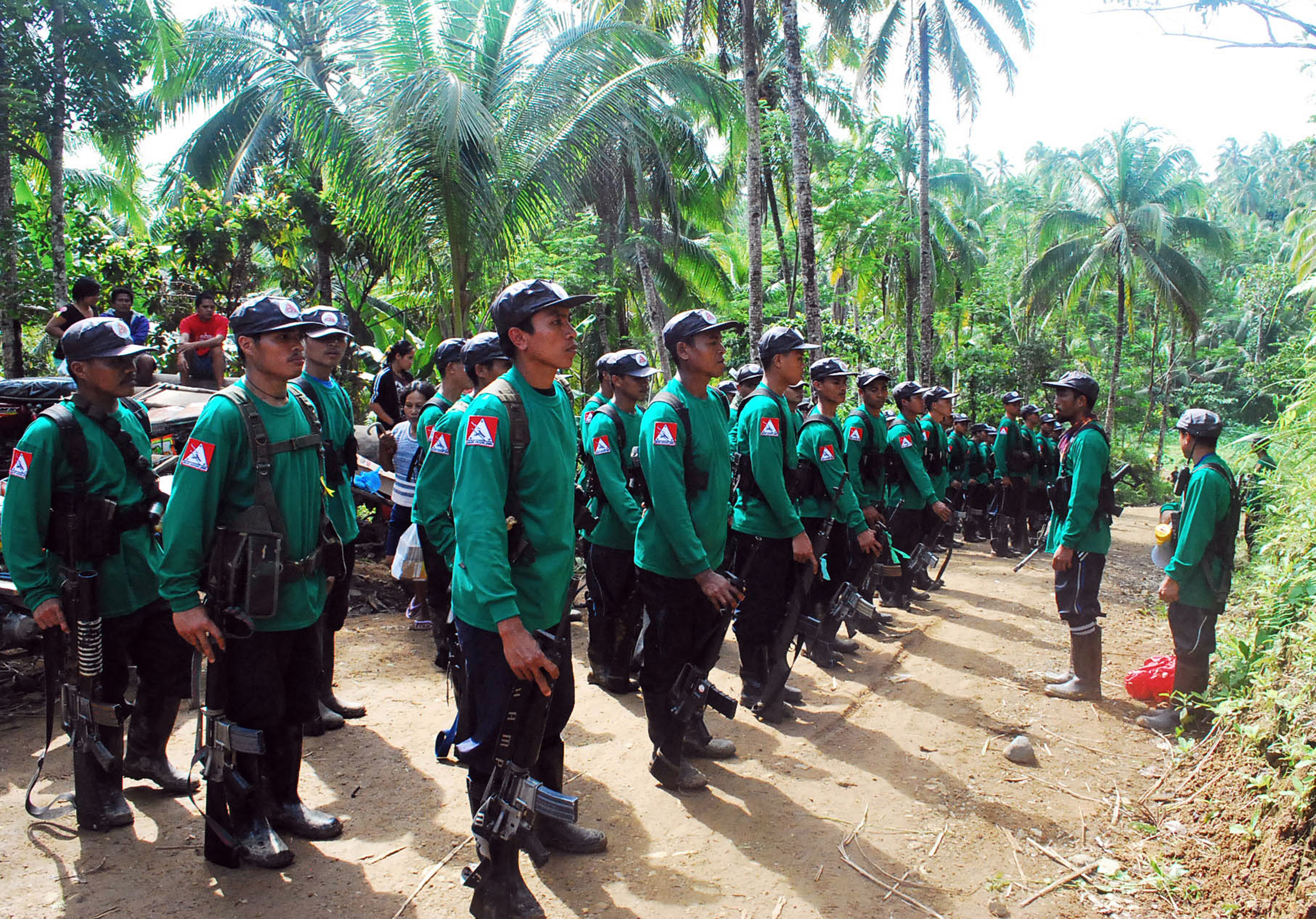 In this file photograph taken on December 26, 2009, New People's Army (NPA) rebels stand to attention during the 41st founding anniversary of the Communist Party of the Philippines at an unspecified location in the hinterlands of Surigao del Sur province, in the southern Philippine island of Mindanao. / AFP PHOTO / MITCHELL MADURO / XGTY