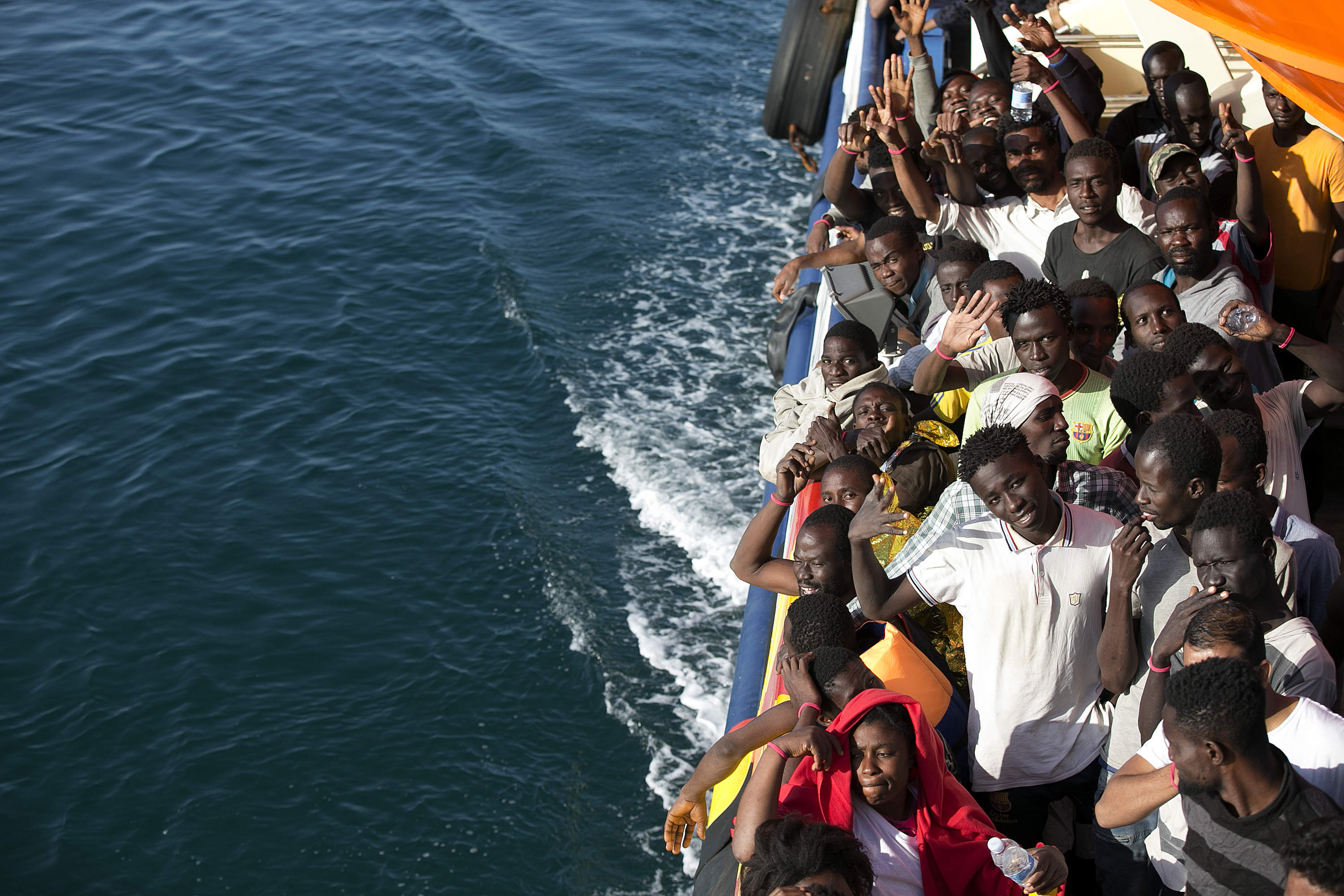 A handout picture taken and released on August 20, 2016 by the Italian Red Cross shows migrants aboard a rescue boat run by the Malta-based NGO Migrant Offshore Aid Station (MOAS) and the Italian Red Cross (CRI), as they arrive at the port of Trapani.  Two Syrian girls, one of them an eight-month-old baby, are among up to six people who died when a boat carrying would-be migrants to Europe capsized off Libya on August 18, 2016, rescuers said. Five bodies were recovered and one passenger was missing, presumed drowned, following the capsize. Some of the 21 survivors told aid workers there had been 27 people from eight Syrian families on the boat. / AFP PHOTO / ITALIAN RED CROSS / Yara Nardi / RESTRICTED TO EDITORIAL USE - MANDATORY CREDIT "AFP PHOTO /  ITALIAN RED CROSS / YARA NARDI" - NO MARKETING - NO ADVERTISING CAMPAIGNS - DISTRIBUTED AS A SERVICE TO CLIENTS