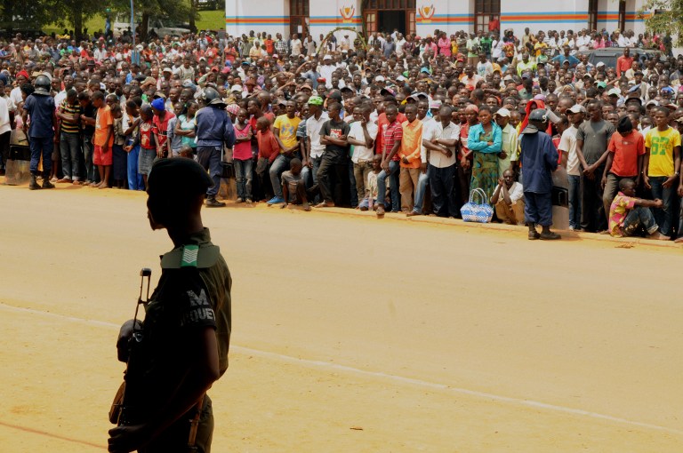 A serviceman of the Armed Forces of the Democratic Republic of Congo (FARDC) stands guard as people gathered to attend the public hearing of suspected members of the Allied Democratic Forces (ADF), a partly Islamist militia of Ugandan origin blamed for the death of hundreds of civilians in eastern DRC, in Beni on August 20, 2016.  Authorities slapped a dawn-to-dusk curfew on two northeast Congo towns on August 18, 2016, following deadly clashes over the government's failure to prevent repeated civilian massacres. The slaying in which victims were the latest in a string of massacres that has left more than 700 dead since 2014. / AFP PHOTO / KUDRA MALIRO