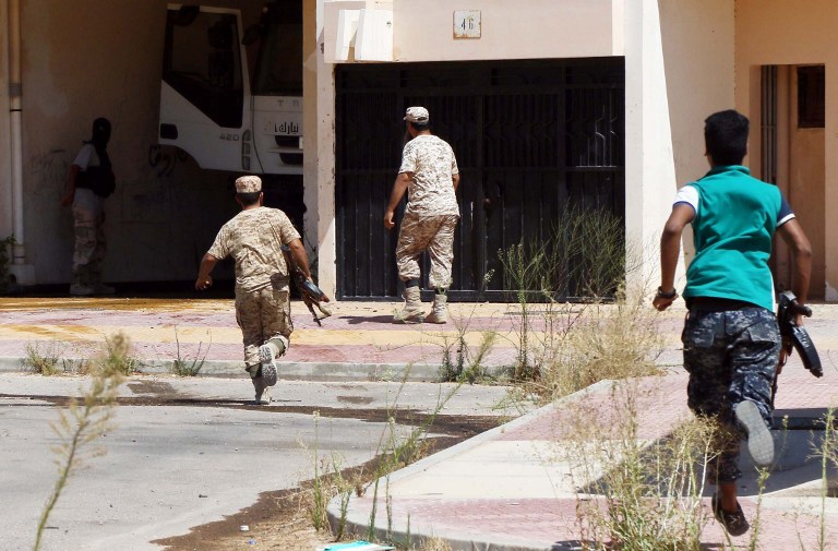 Forces loyal to Libya's UN-backed Government of National Accord (GNA) run towards a building in Sirte, east of the capital Tripoli, as they comb through residential neighbourhoods that were previously controlled by IS, clearing the area of booby traps and car bombs on August 22, 2016. GNA fighters, backed by US air strikes, have recaptured more ground from jihadists holed up in the centre of Sirte in recent days.  / AFP PHOTO / MAHMUD TURKIA