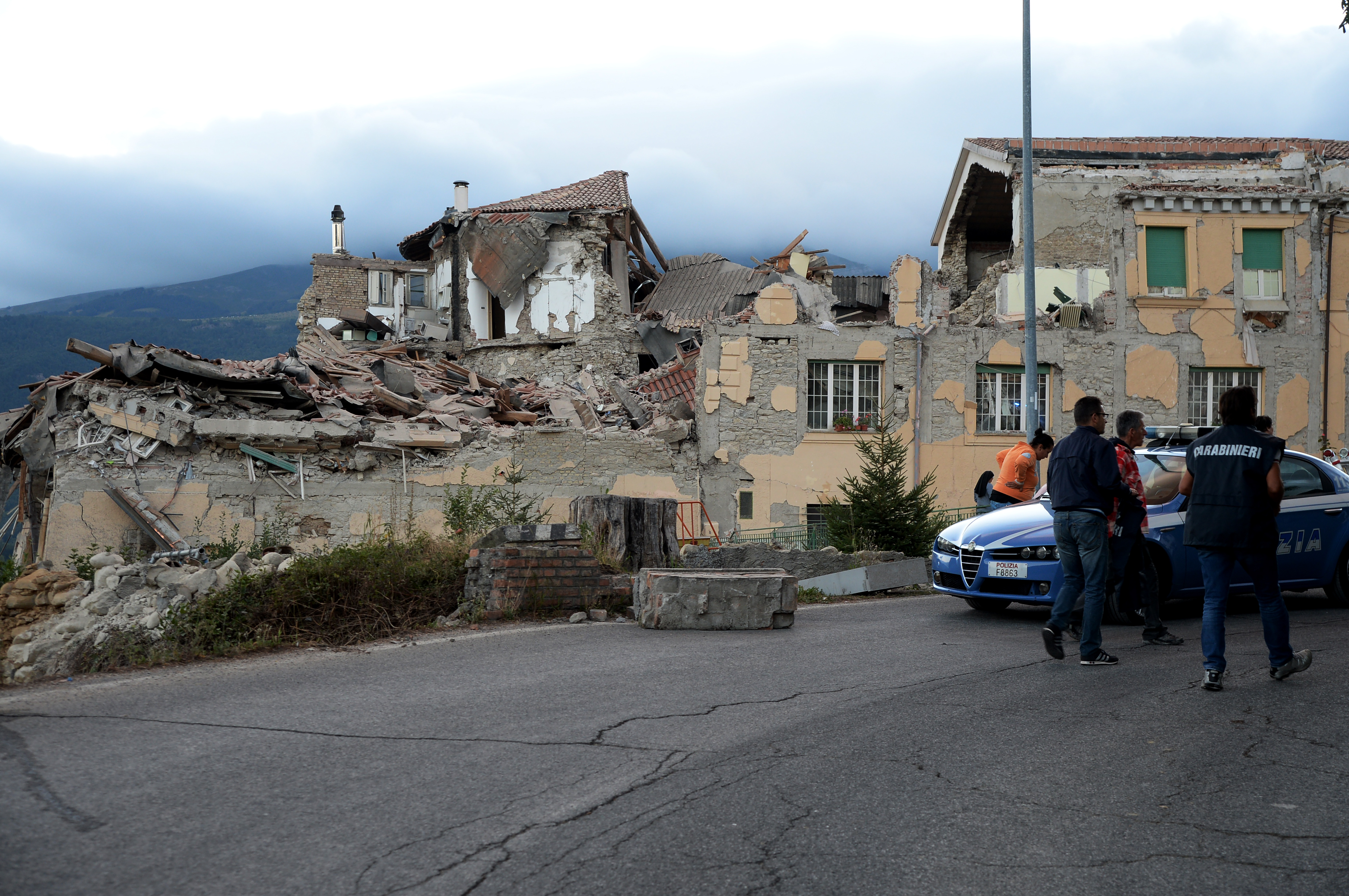 Policemen walk past damaged buildings after a strong heartquake hit Amatrice on August 24, 2016. Central Italy was struck by a powerful, 6.2-magnitude earthquake in the early hours, which has killed at least three people and devastated dozens of mountain villages. Numerous buildings had collapsed in communities close to the epicenter of the quake near the town of Norcia in the region of Umbria, witnesses told Italian media, with an increase in the death toll highly likely. / AFP PHOTO / FILIPPO MONTEFORTE