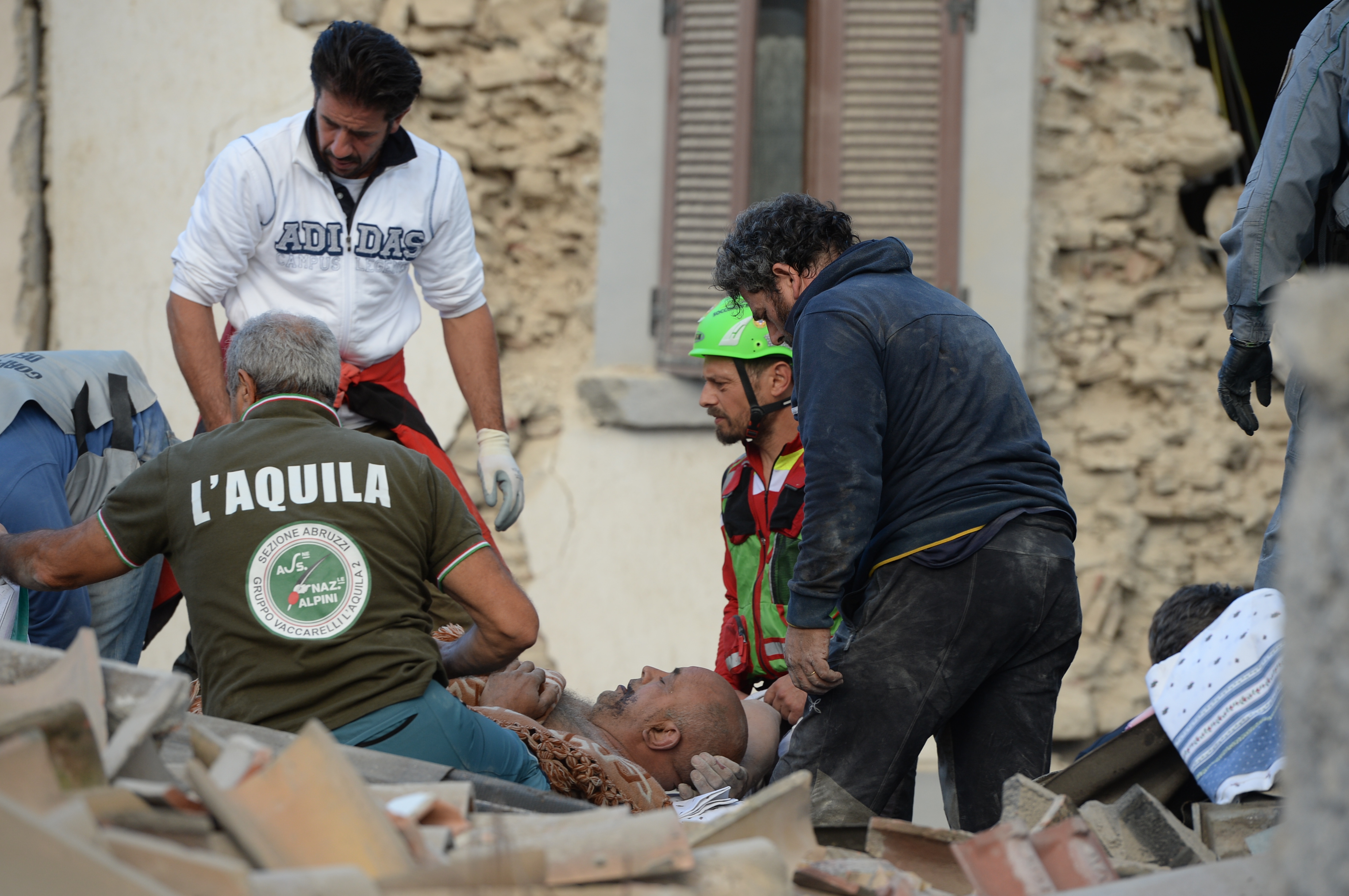 Rescuers help a victim in a damaged building after a strong heartquake hit Amatrice on August 24, 2016. Central Italy was struck by a powerful, 6.2-magnitude earthquake in the early hours, which has killed at least three people and devastated dozens of mountain villages. Numerous buildings had collapsed in communities close to the epicenter of the quake near the town of Norcia in the region of Umbria, witnesses told Italian media, with an increase in the death toll highly likely. / AFP PHOTO / FILIPPO MONTEFORTE