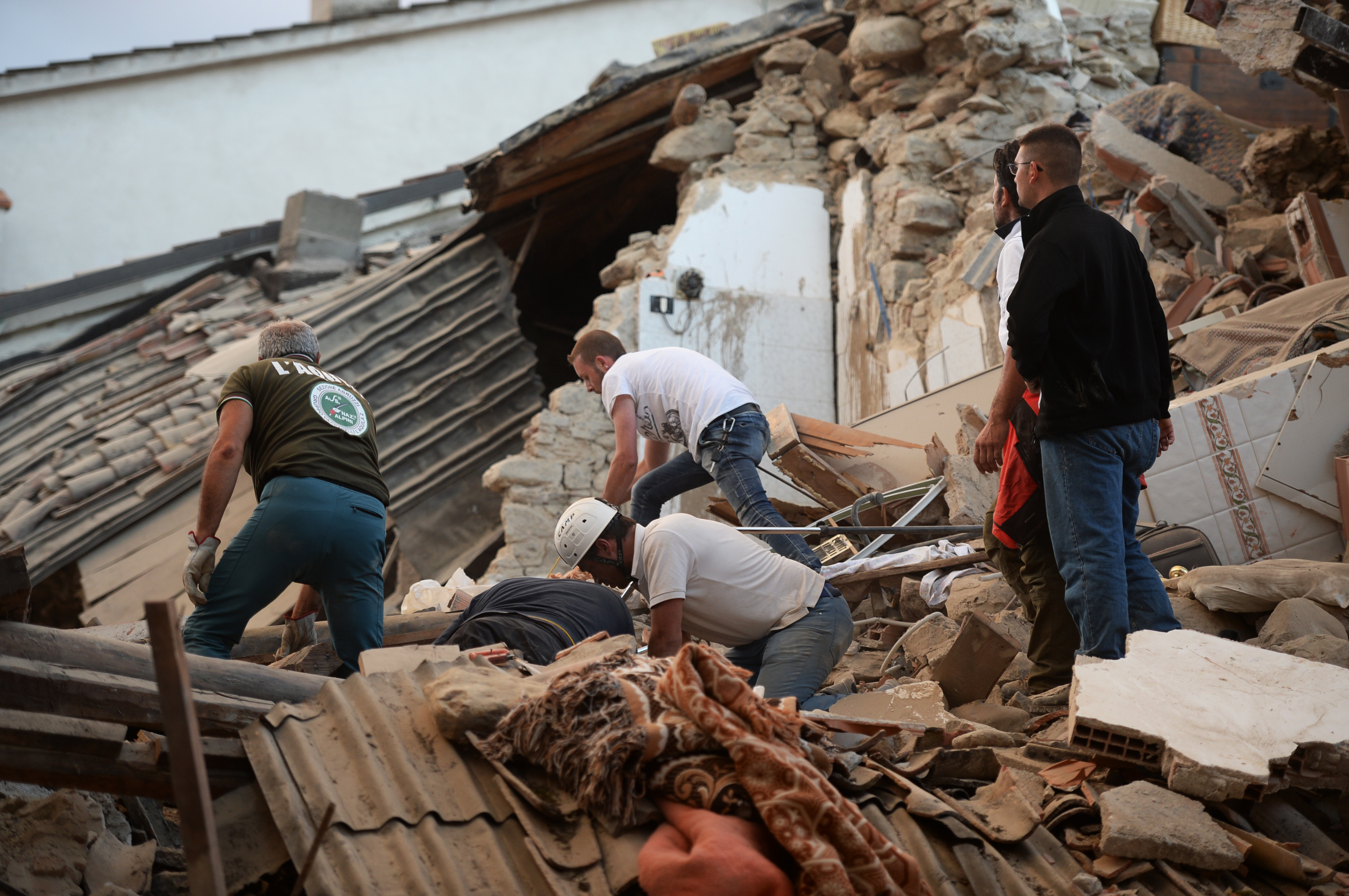 Rescuers and residents search for victims among damaged buildings after a strong heartquake hit Amatrice on August 24, 2016. Central Italy was struck by a powerful, 6.2-magnitude earthquake in the early hours, which has killed at least three people and devastated dozens of mountain villages. Numerous buildings had collapsed in communities close to the epicenter of the quake near the town of Norcia in the region of Umbria, witnesses told Italian media, with an increase in the death toll highly likely. / AFP PHOTO / FILIPPO MONTEFORTE