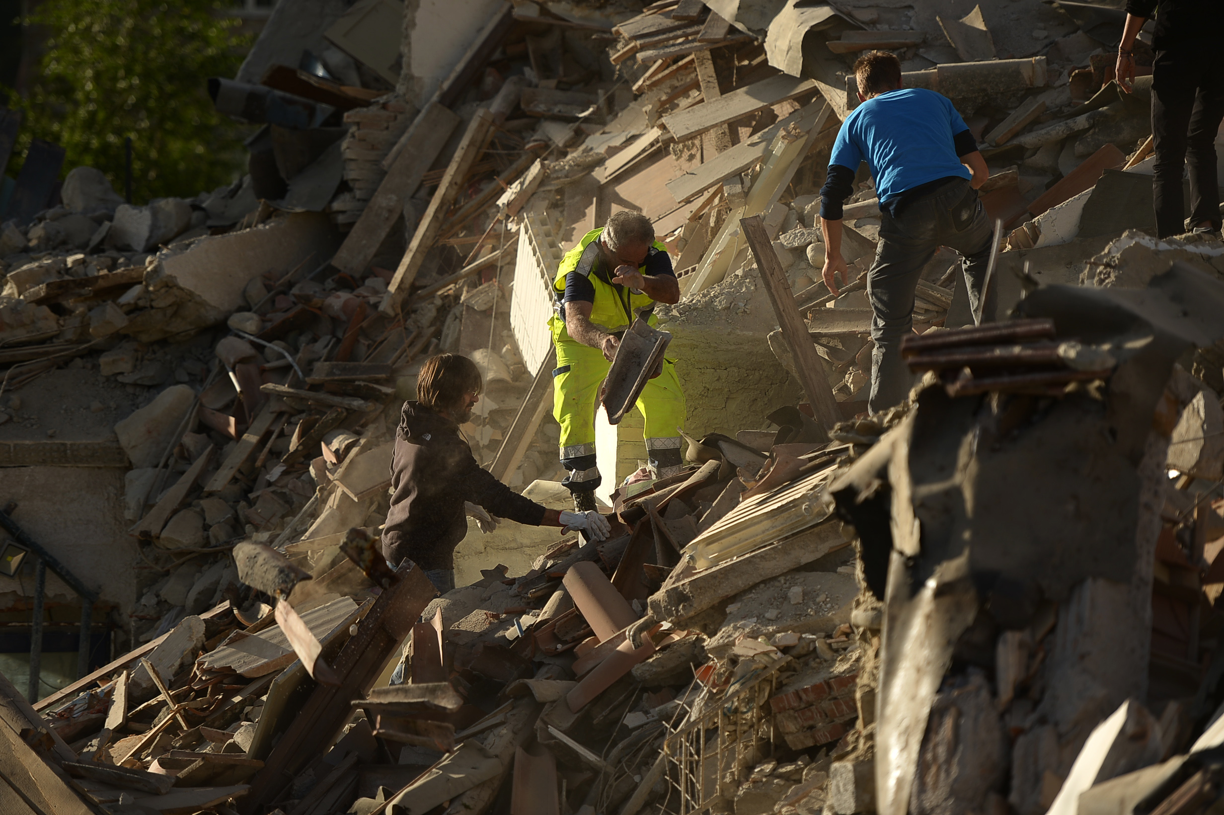 Resucers and residents clear debris in search for victims in damaged homes after a strong heathquake hit Amatrice on August 24, 2016. Central Italy was struck by a powerful, 6.2-magnitude earthquake in the early hours, which has killed at least three people and devastated dozens of mountain villages. Numerous buildings had collapsed in communities close to the epicenter of the quake near the town of Norcia in the region of Umbria, witnesses told Italian media, with an increase in the death toll highly likely. / AFP PHOTO / FILIPPO MONTEFORTE