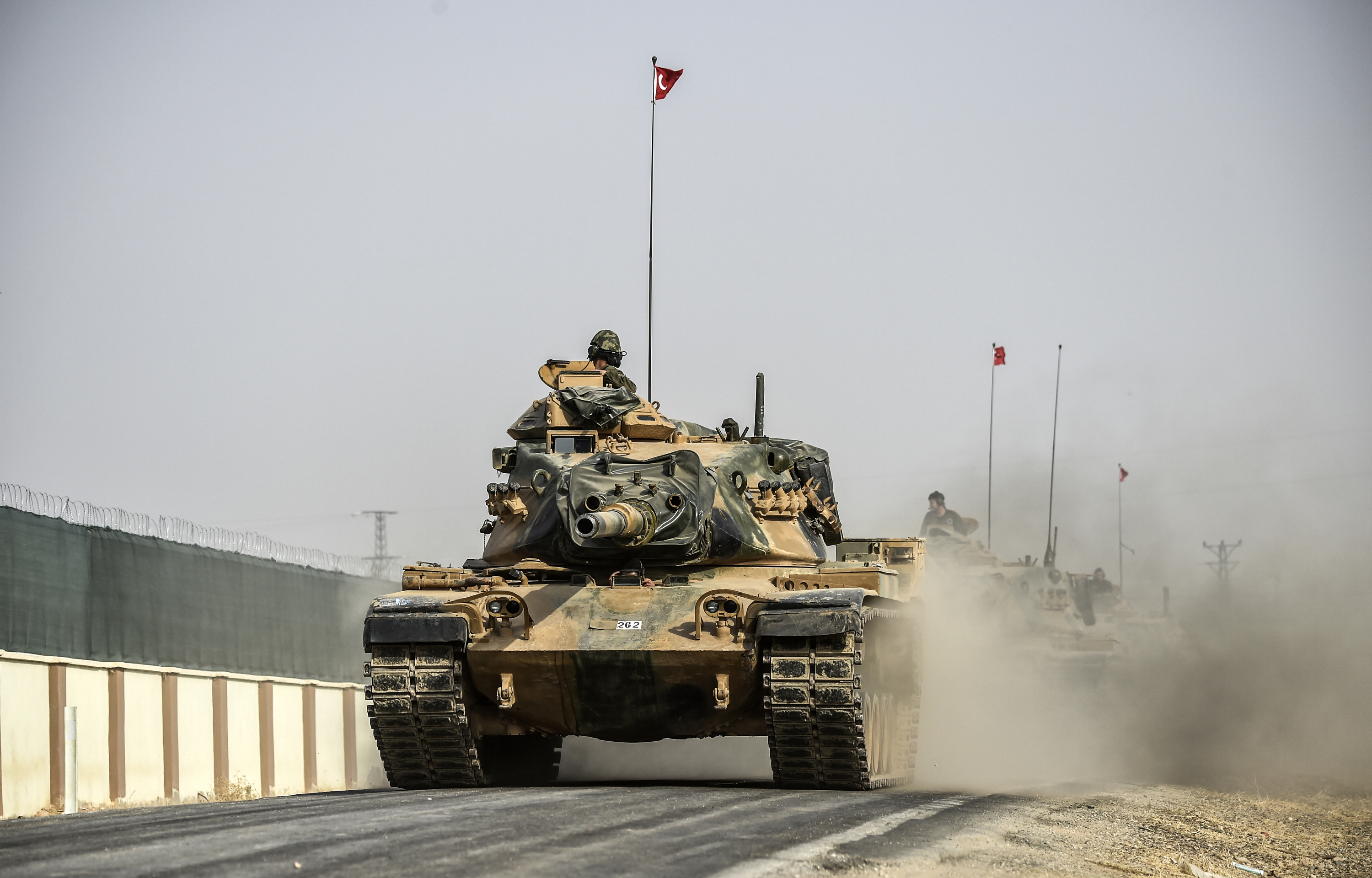This picture taken around 5 kilometres west from the Turkish Syrian border city of Karkamis in the southern region of Gaziantep, on August 25, 2016 shows Turkish Army tanks driving to the Syrian Turkish border town of Jarabulus. Turkey's army backed by international coalition air strikes launched an operation involving fighter jets and elite ground troops to drive Islamic State jihadists out of a key Syrian border town. The air and ground operation, the most ambitious launched by Turkey in the Syria conflict, is aimed at clearing jihadists from the town of Jarabulus, which lies directly opposite the Turkish town of Karkamis. / AFP PHOTO / BULENT KILIC