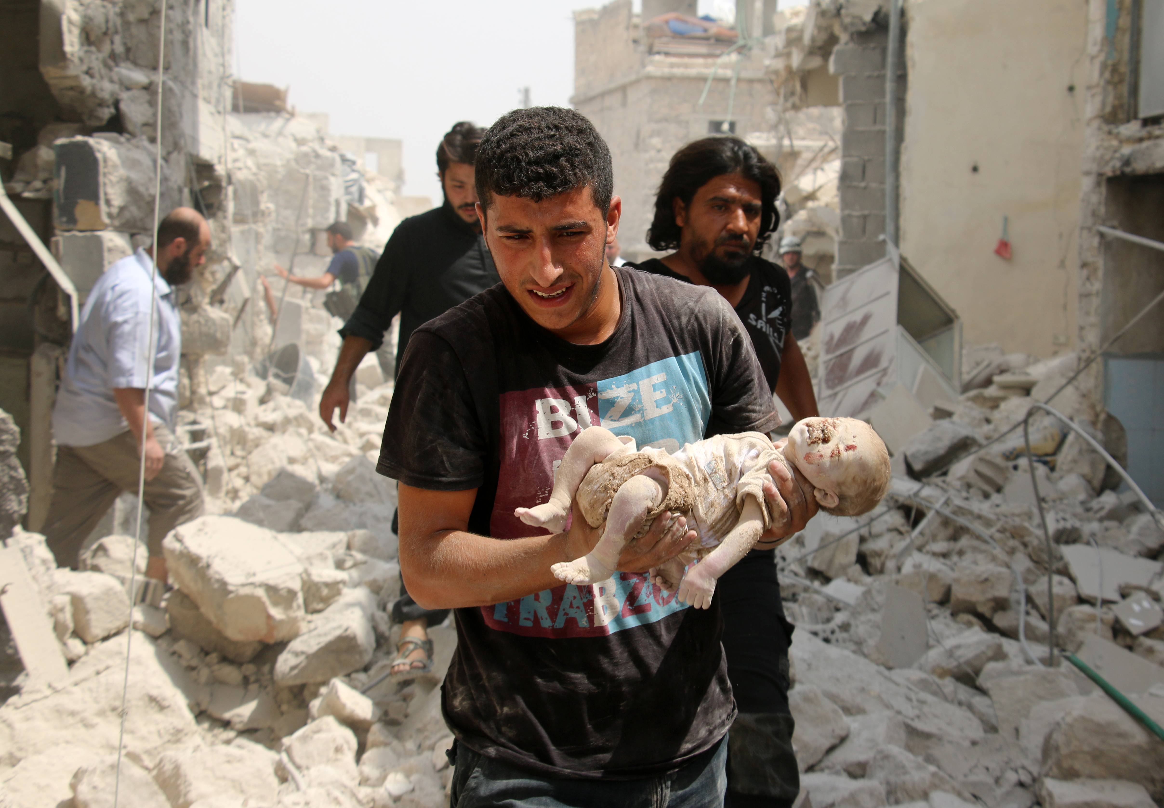 EDITORS NOTE: Graphic content / A Syrian man carries a dead baby in the rubble of buildings following a barrel bomb attack on the Bab al-Nairab neighbourhood of the northern Syrian city of Aleppo on August 25, 2016.  At least fifteen civilians, among them eleven children were killed in a barrel bomb attack carried out by government forces on a rebel-held neighbourhood of Syria's Aleppo city, according to the Syrian Observatory for Human Rights. / AFP PHOTO / AMEER ALHALBI