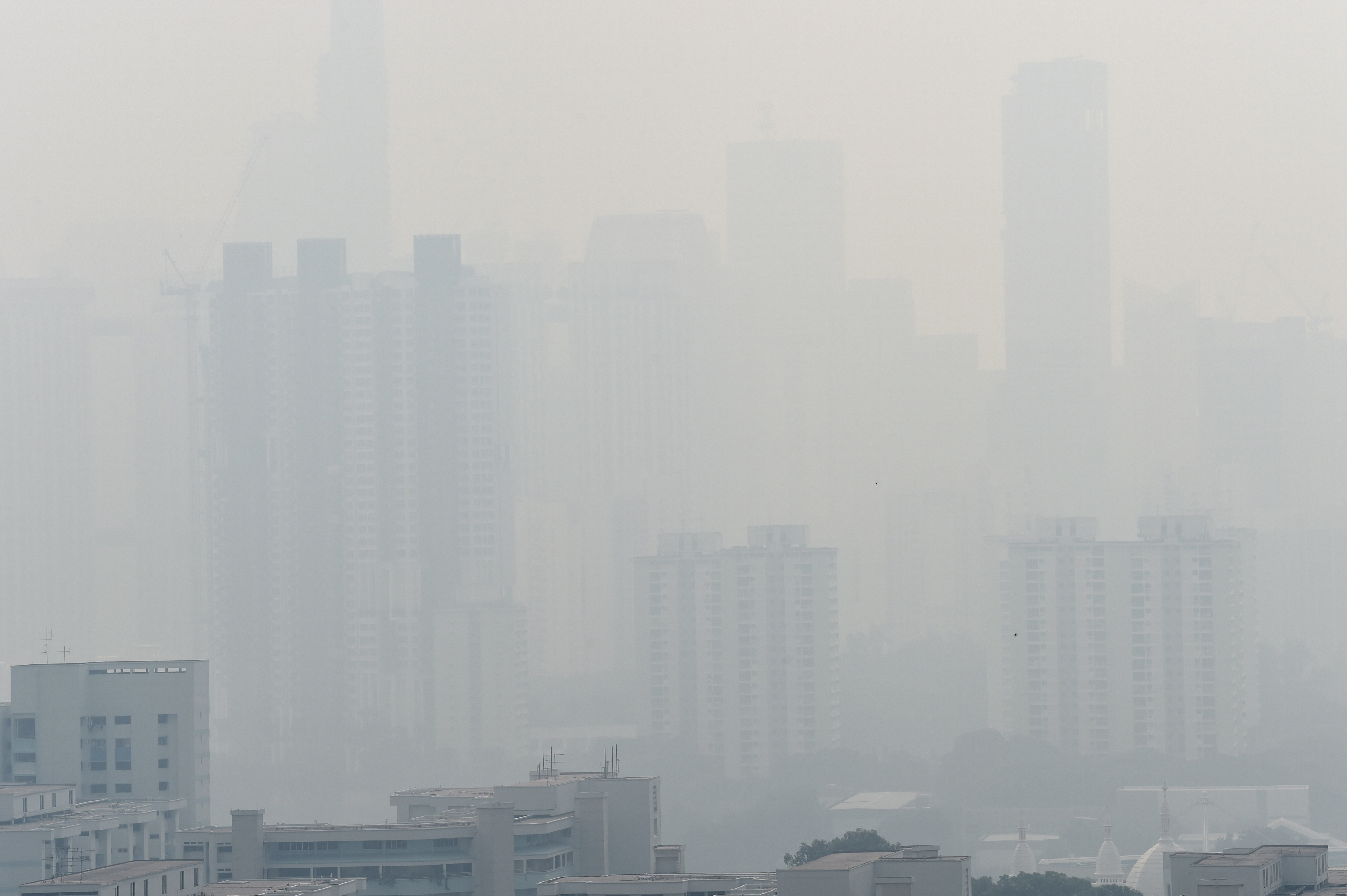 The city skyline (background) hardly visible due to haze in Singapore on August 26, 2016. Smog and a strong acrid smell blanketed Singapore on August 26 as smoke from forest fires in Indonesia blew into the city-state, sending the air quality index to unhealthy levels. / AFP PHOTO / ROSLAN RAHMAN
