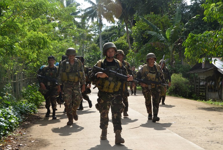 Philippine soldiers walk along a highway as they return to camp after an armed encounter with members of militant group Abu Sayyaf at the village of Bongkaong, Patikul town, Sulu province on the southern island of Mindanao on August 26, 2016.  Philippine security officials killed six members of militant group Abu Sayyaf on August 26 including one involved in the kidnapping of two Canadians who were beheaded in the troubled south, the military said. / AFP PHOTO / STRINGER