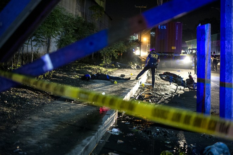 EDITORS NOTE: Graphic content / Philippine Scene of the Crime Operatives (SOCO) work at the scene where two suspects were shot dead following an encouter and shootout with police at a checkpoint along a highway in Manila on August 28, 2016. More than 2,000 people have died violent deaths since Duterte took office two months ago and immediately implemented his scorched-earth plans to eradicate drugs in society, ordering police to shoot dead traffickers and urging ordinary citizens to kill addicts. The bloodbath has seen unknown assailants kill more than half the victims, according to police statistics, raising fears that security forces and hired assassins are roaming through communities and shooting dead anyone suspected of being involved in drugs. / AFP PHOTO / NOEL CELIS / TO GO WITH AFP STORY PHILIPPINES-POLITICS-CRIME-RIGHTS-ADDICTION,FOCUS BY CECIL MORELLA