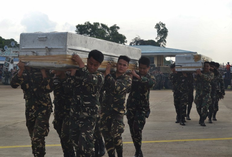 Philippine soldiers carry caskets containing bodies of colleagues killed in an encounter with Muslim extremist Abu Sayyaf group, into a C-130 cargo plane at Jolo airport in Sulu province on the island of Mindanao, on August 30, 2016. Fighters of the Muslim extremist Abu Sayyaf group killed 15 soldiers as they were carrying out President Rodrigo Duterte's order to wipe out the feared group, officials said on August 30. / AFP PHOTO / STR
