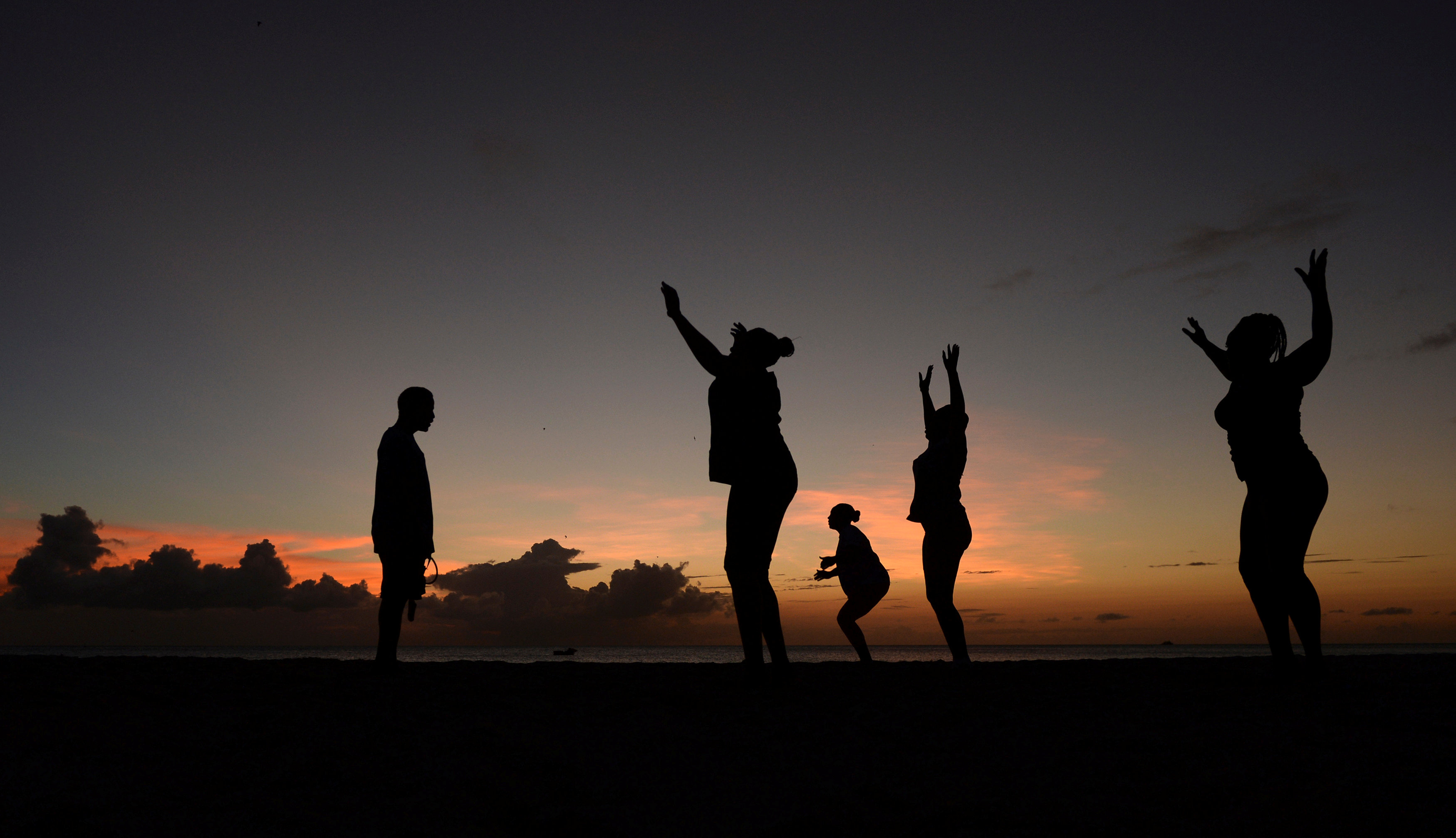 Women exercise in front of a trainer (L) as the sun sets near Kensington Oval in Bridgetown, Barbados March 13, 2014. REUTERS/Philip Brown/File Photo