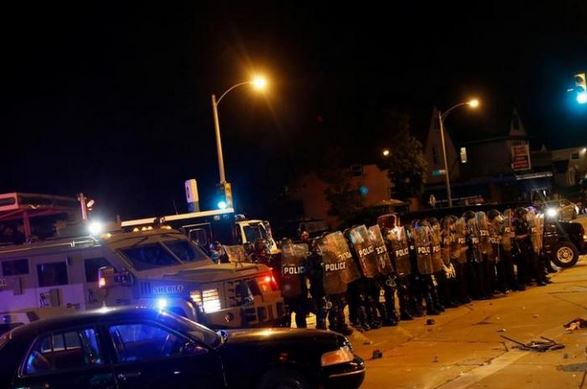 Police stand guard during disturbances following the police shooting of a man in Milwaukee, Wisconsin. REUTERS/Aaron P. Bernstein