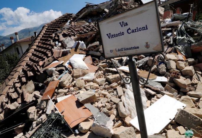 A road sign is seen in front of a collapsed house following an earthquake in Amatrice, central Italy, August 26, 2016. REUTERS/Ciro De Luca