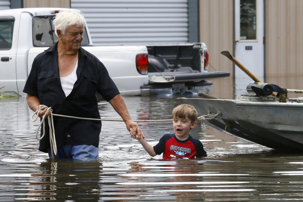 Richard Rossi and his 4 year old great grandson Justice wade through water in search of higher ground after their home took in water in St. Amant, Louisiana. REUTERS/Jonathan Bachman