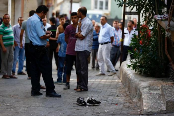 A police officer secures the scene of an explosion as locals stand next to him after a suspected suicide bomber targeted a wedding celebration in the Turkish city of Gaziantep, Turkey, August 21, 2016. REUTERS/Osman Orsal