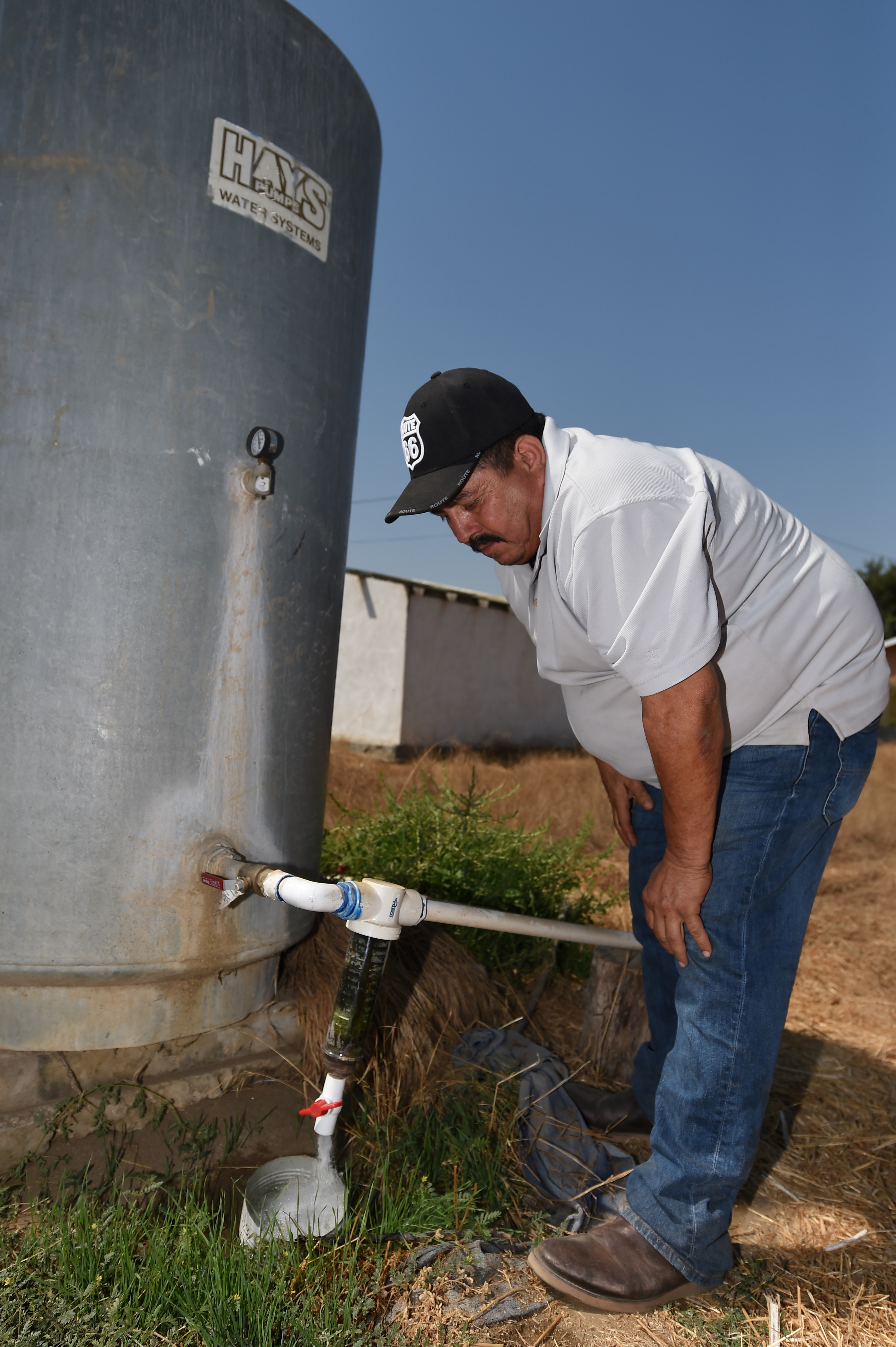 Cristobal Chavez turns on the table on his family's water well at his home, August 24, 2016 in Porterville in California's Central Valley. For many years Chavez, wife and children drank the well water but recently discovered the water is contamined with three times the legal limit of nitrates making it too dangerous to drink. Chavez' home is surrounded by dairy fields, where large dairy operations use cow manure to irrigate their feed crops. Manure as well as agricultural fertilizer is believed to be responsible for the exceptionally high level of nitrate which makes well water undrinkable in many areas of this farming community about 160 miles north of Los Angeles.  / AFP PHOTO / Robyn BECK
