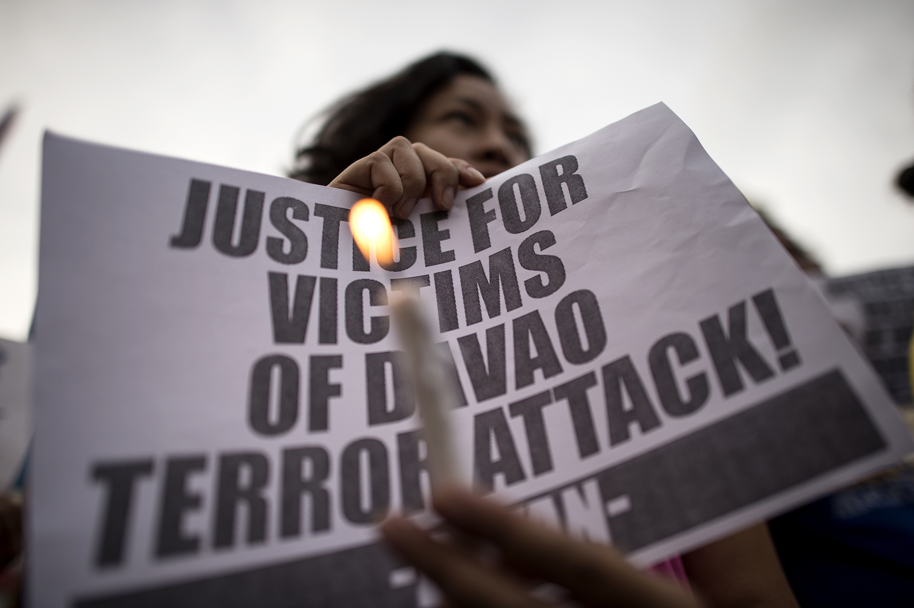 Human rights group members hold candles and burn placards as they stage a protest in front of Quiapo Church in Manila on September 3, 2016, condemning the bombing of a night market in Davao City.   Philippine authorities on September 3 blamed a notorious group of Islamic militants for the bombing of a night market in President Rodrigo Duterte's home town that killed at least 14 people. / AFP PHOTO / NOEL CELIS