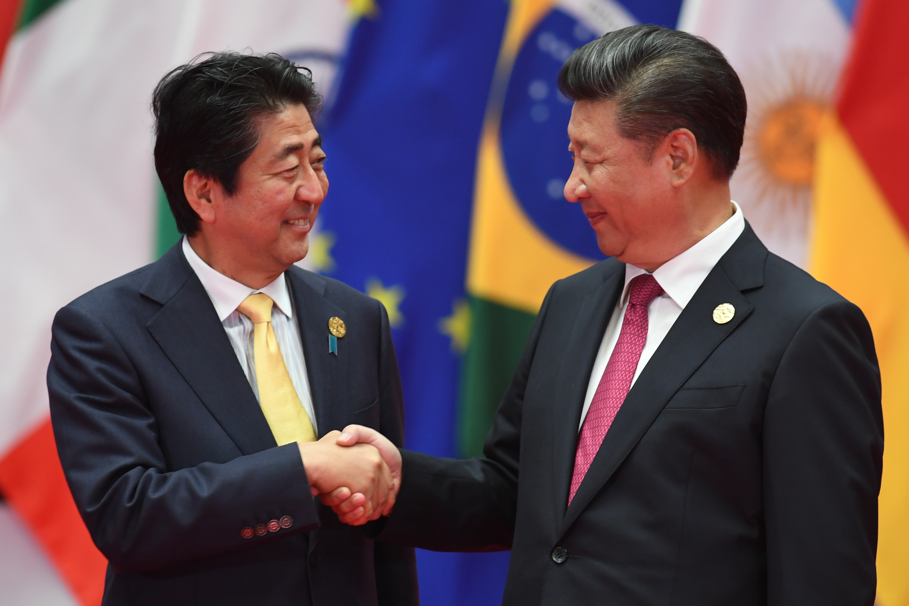 Japan's Prime Minister Shinzo Abe (L) shakes hands with China's President Xi Jinping (R) before the G20 leaders' family photo in Hangzhou on September 4, 2016. World leaders are gathering in Hangzhou for the 11th G20 Leaders Summit from September 4 to 5. / AFP PHOTO / Greg BAKER