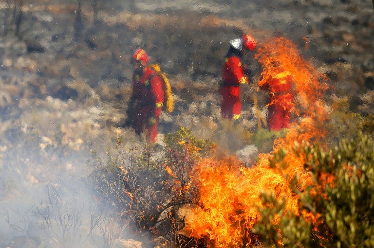 Firefighters fight a wildfire next to a residential area along the coastline near the Spanish resort of Javea, Valencia region, on September 5, 2016. More than 1,000 people were evacuated after a wildfire fuelled by intense heat roared through brush surrounding a popular tourist resort on Spain's Costa Blanca, officials said today.  / AFP PHOTO / Manuel Lorenzo