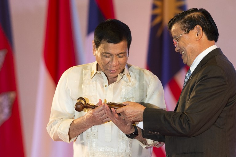 Philippine President Rodrigo Duterte accepts the gavel from Laos Prime Minister Thongloun Sisoulith during the closing ceremony of the Association of Southeast Asian Nations (ASEAN) and handover of the ASEAN Chairmanship to the Philippines in Vientiane on September 8, 2016. ASEAN leaders gather in Vientiane for the 28th and 29th ASEAN Summits held between September 6 to 8. / AFP PHOTO / YE AUNG THU