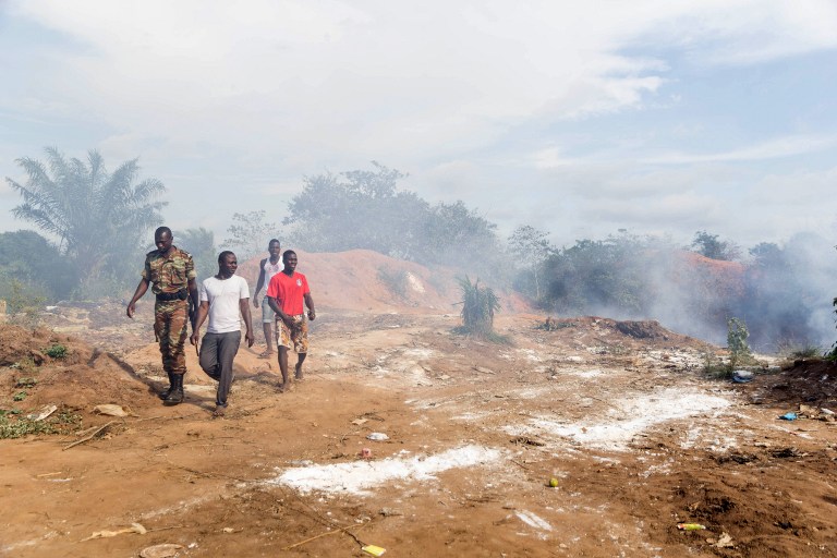 A policeman and members of the public leave the scene of an explosion at a garbage dump that left two people dead in Cotonou on September 9, 2016.  At least two people were killed scores more injured after an explosion at a garbage dump in Benin, police told AFP on September 9. The blast happened on the evening of September 8, with the fire erupting in Tori Avame, 40 kilometres (25 miles) from Benin's commercial hub, Cotonou.   / AFP PHOTO / YANICK FOLLY