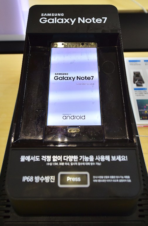A Galaxy Note 7 smartphone is on display in a waterproof-testing case at a mobile phone shop in Seoul on September 12, 2016. Samsung shares plunged on September 12 after the South Korean electronics giant urged global users to stop using its Galaxy Note 7 smartphone due to a spate of exploding batteries that raised alarm around the world. / AFP PHOTO / JUNG YEON-JE