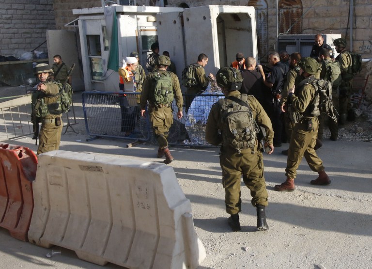 Israeli soldiers cover the body of a Palestinian who was shot dead after reportedly carrying out a stabbing attack on a soldier near the Jewish settler enclave of Tal Rumeda in the city centre of the West Bank town of Hebron on September 16, 2016. Three alleged assailants were killed while carrying out attacks on Israelis, security forces said, shattering weeks of relative calm in Israel and the Palestinian territories. / AFP PHOTO / HAZEM BADER