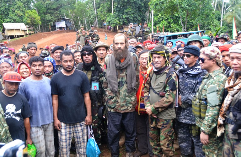 Moro National Liberation Front (MNLF) chairman Nur Misuari (4th R) poses for photos with freed Norwegian national Kjartan Sekkingstad (C), and three Indonesians (front L-R) during their turn-over ceremony in Indanan town, Sulu province, in southern island of Mindanao on September 18, 2016.  A Norwegian and three Indonesian seamen held hostage in the southern Philippines were turned over to a government envoy on September 18 after being freed by Islamic extremists who had beheaded two captives earlier this year. / AFP PHOTO / NICKEE BUTLANGAN