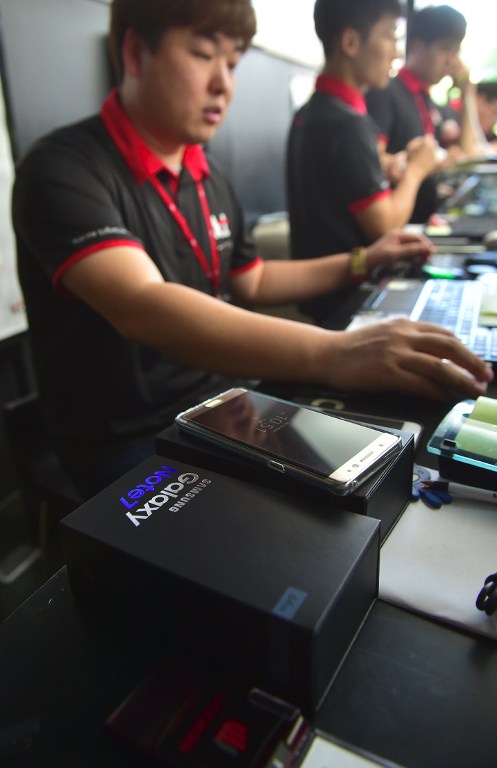 A South Korean employee works to provide replacement Samsung Galaxy Note7 smartphones at a telecommunications shop in Seoul on September 19, 2016. Samsung started on September 19 to provide users of its Galaxy Note 7 smartphone the first batch of replacements with new batteries, after a series of battery explosions prompted a major recall worldwide. / AFP PHOTO / JUNG YEON-JE