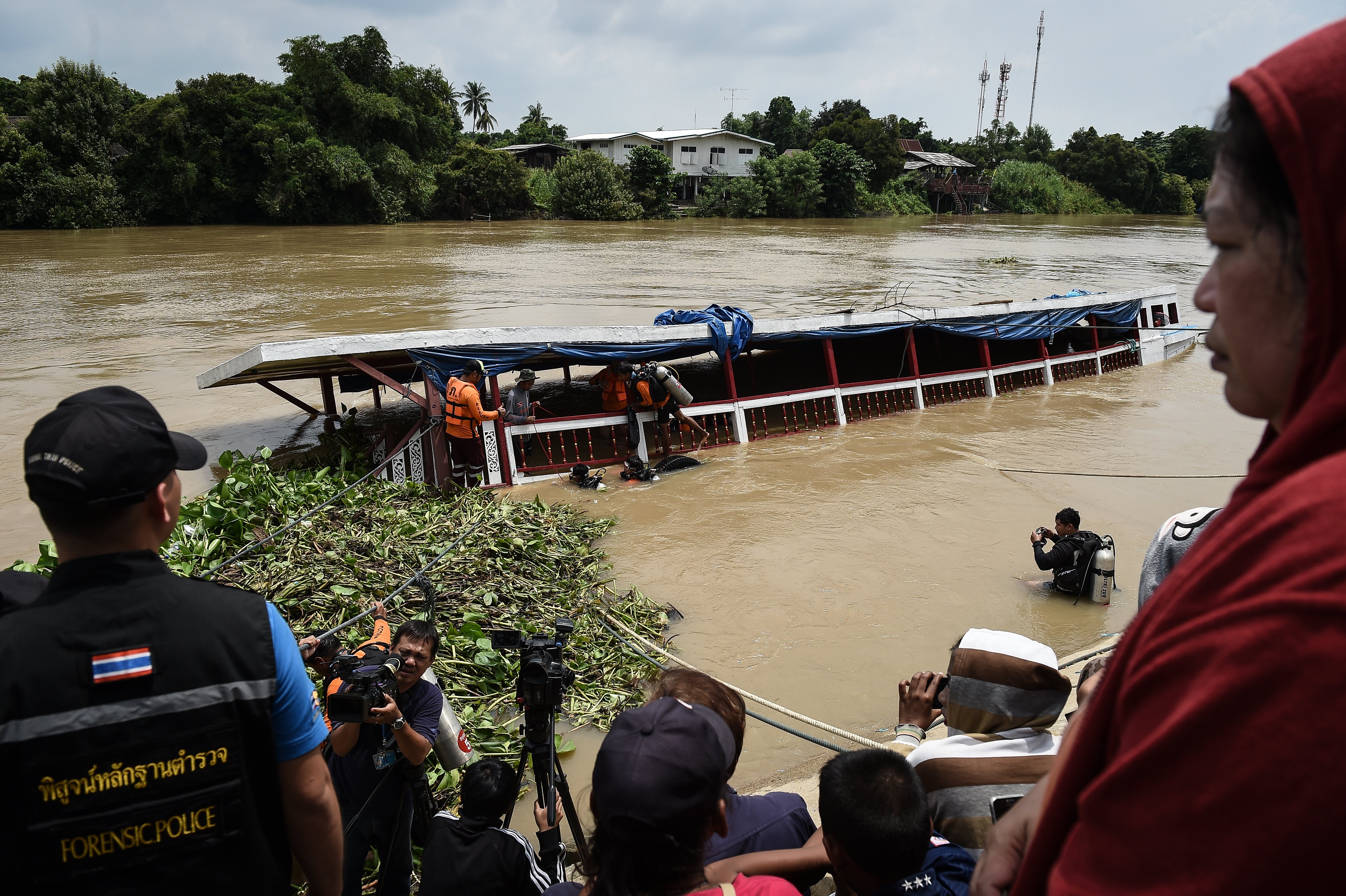 Rescue workers look for missing persons on a ferry which capsized the day before in the province of Ayutthaya on September 19, 2016. Divers resumed the search on September 19 for missing passengers after an overcrowded boat carrying Muslim pilgrims sank on Thailand's Chao Phraya river, leaving at least 15 people dead.  / AFP PHOTO / LILLIAN SUWANRUMPHA