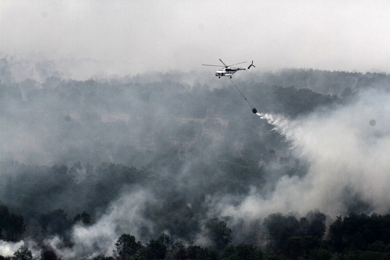 (FILES) This file picture taken on October 17, 2015 shows a MI-17 helicopter run by the Indonesian National Disaster Mitigation Agency conducting water-bombs on a fire spot in Ogan Komering Ilir area in South Sumatra province. A smog outbreak in Southeast Asia last year may have caused over 100,000 premature deaths, according to a new study released on September 19, 2016 that triggered calls for action to tackle the "killer haze". / AFP PHOTO / ABDUL QODIR