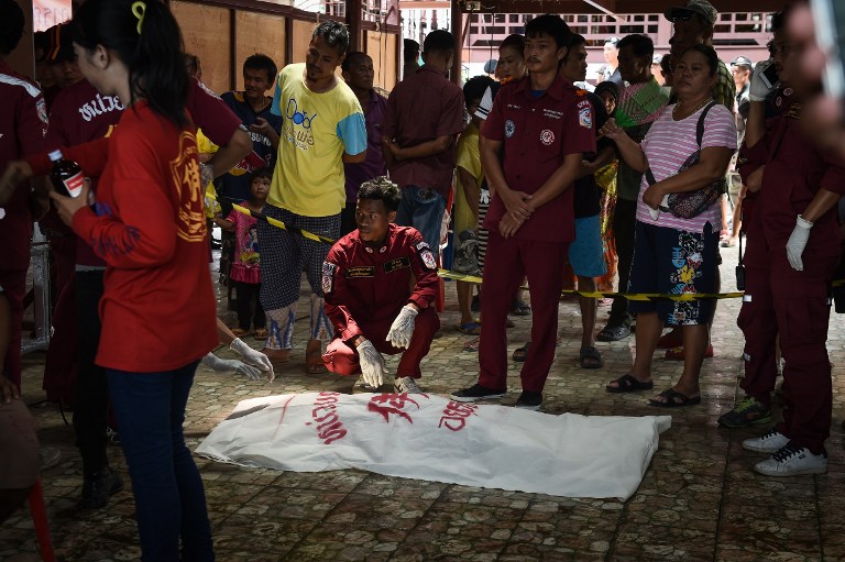 The body of an 8-year-old boy is attended to by rescue workers after being recovered from a ferry which capsized the day before in an accident in the province of Ayutthaya on September 19, 2016. Divers resumed the search Monday for missing passengers after an overcrowded boat carrying Muslim pilgrims sank on Thailand's Chao Phraya river leaving at least 15 people dead, officials said. / AFP PHOTO / LILLIAN SUWANRUMPHA