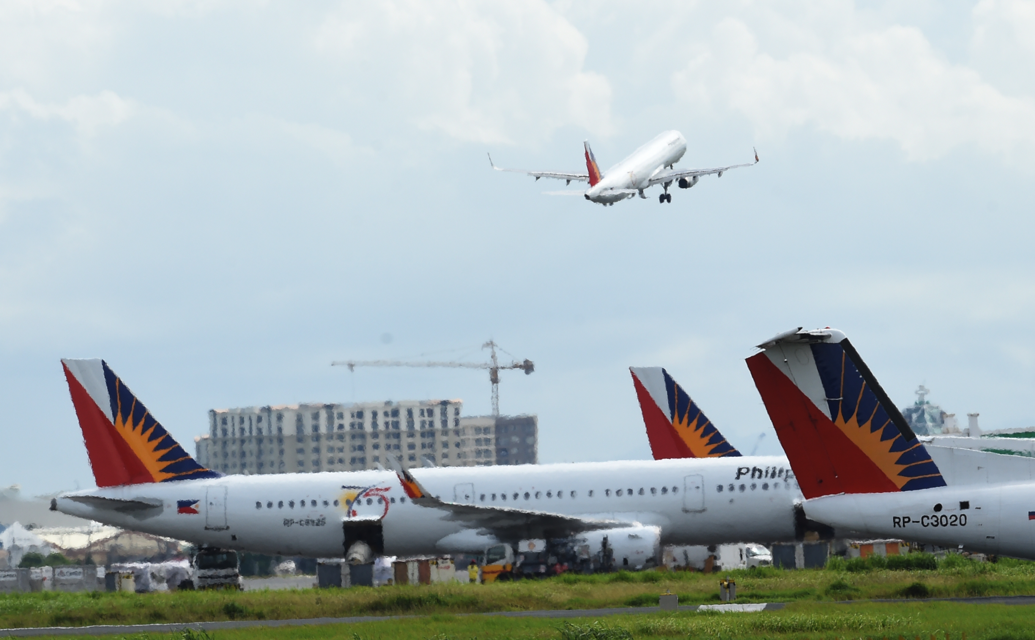 In this photo tatken on September 13, 2016 shows Philippine airlines planes are parked while another takes off at the international airport of Manila. / AFP PHOTO / TED ALJIBE