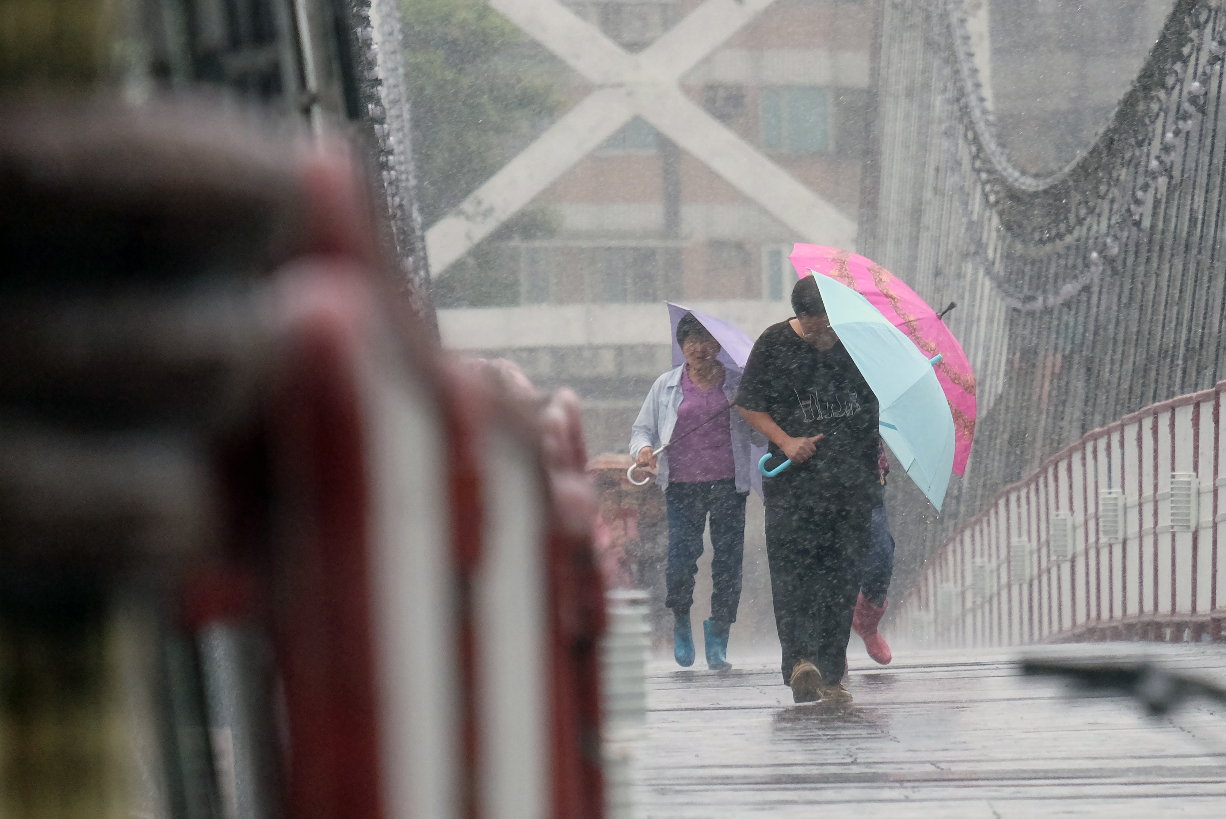 Local residents walk on a suspension bridge in Bitan in the New Taipei City, as Typhoon Megi approaching the east Taiwan on September 27, 2016.  Typhoon Megi churns towards Taiwan with powerful winds and rains in the third typhoon to hit the island in two weeks. / AFP PHOTO / SAM YEH