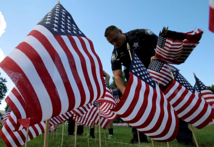 A police officer plants some of the 3,000 U.S. flags placed in memory of the lives lost in the September 11, 2001 attacks, at a park in Winnetka, Illinois, September 10, 2016. REUTERS/Jim Young