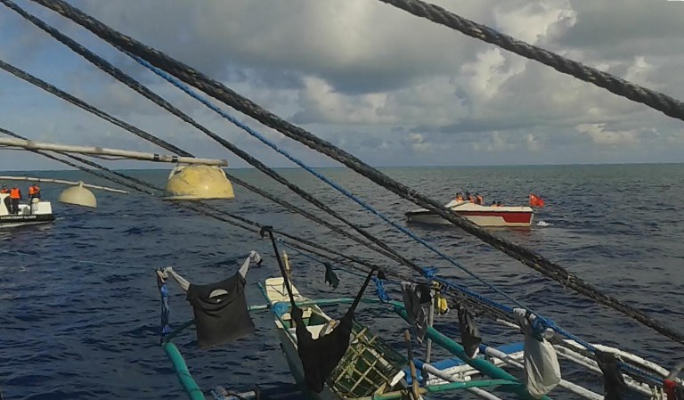 This smartphone photo taken on June 7, 2016 by a Filipino fisherman and released to Agence France-Presse on June 16 shows Chinese coast guard personnel on speed boats (back L and R) blocking a Philippine fishing vessel at Scarborough Shoal. The incident at Scarborough Shoal, a necklace of reefs and rocks that Filipino fishermen say hosts some of the world's most abundant marine life, is part of a long-running territorial row that sits at the heart of a UN backed tribunal expected to rule in the coming weeks. / AFP PHOTO / STR / TO GO WITH Philippines-China-UN-maritime-diplomacy-fishing,FOCUS by Cecil Morella