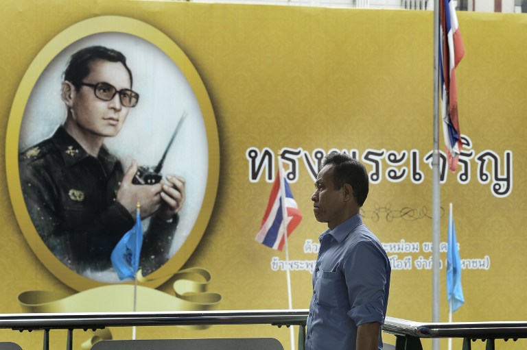 A man walks past a photograph of Thai King Bhumibol Adulyadej in Bangkok on September 13, 2016. / AFP PHOTO / MUNIR UZ ZAMAN