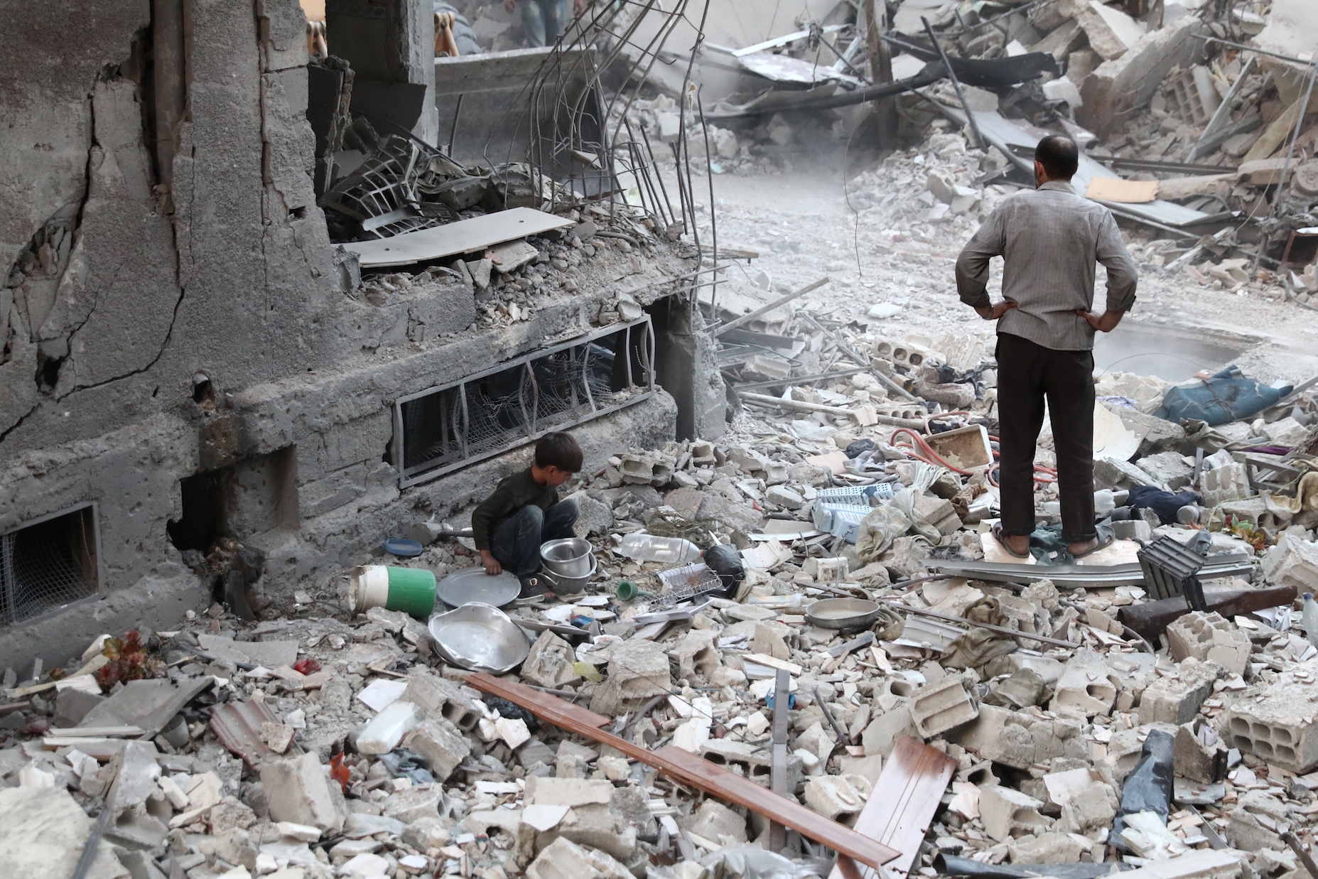 A Syrian boy collects items amidst the rubble of destroyed buildings on October 3, 2016, following reported air strikes in the rebel-held town of Douma, on the eastern outskirts of the capital Damascus. Air strikes shook a besieged rebel-held town east of the Syrian capital, sparking fears among civilians of a fate similar to battered Aleppo city. More than a dozen raids and several mortar rounds pounded Douma, said the Syrian Observatory for Human Rights monitoring group. / AFP PHOTO / Abd Doumany