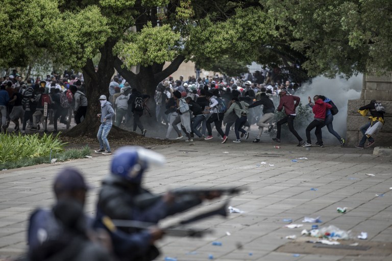 Students at the University of Witwatersrand confront South African anti-riot policemen during a running battle with the police forces on campus during a mass demonstration on October 4, 2016 in Johannesburg.  South African police fired rubber bullets, stun grenades and teargas at student protesters in Johannesburg as authorities tried to re-open the prestigious Wits University after weeks of demonstrations. The university, along with many campuses across South Africa, has been closed for at least two weeks during protests over tuition fees, with violent clashes regularly erupting between students, police and private security guards. / AFP PHOTO / MARCO LONGARI