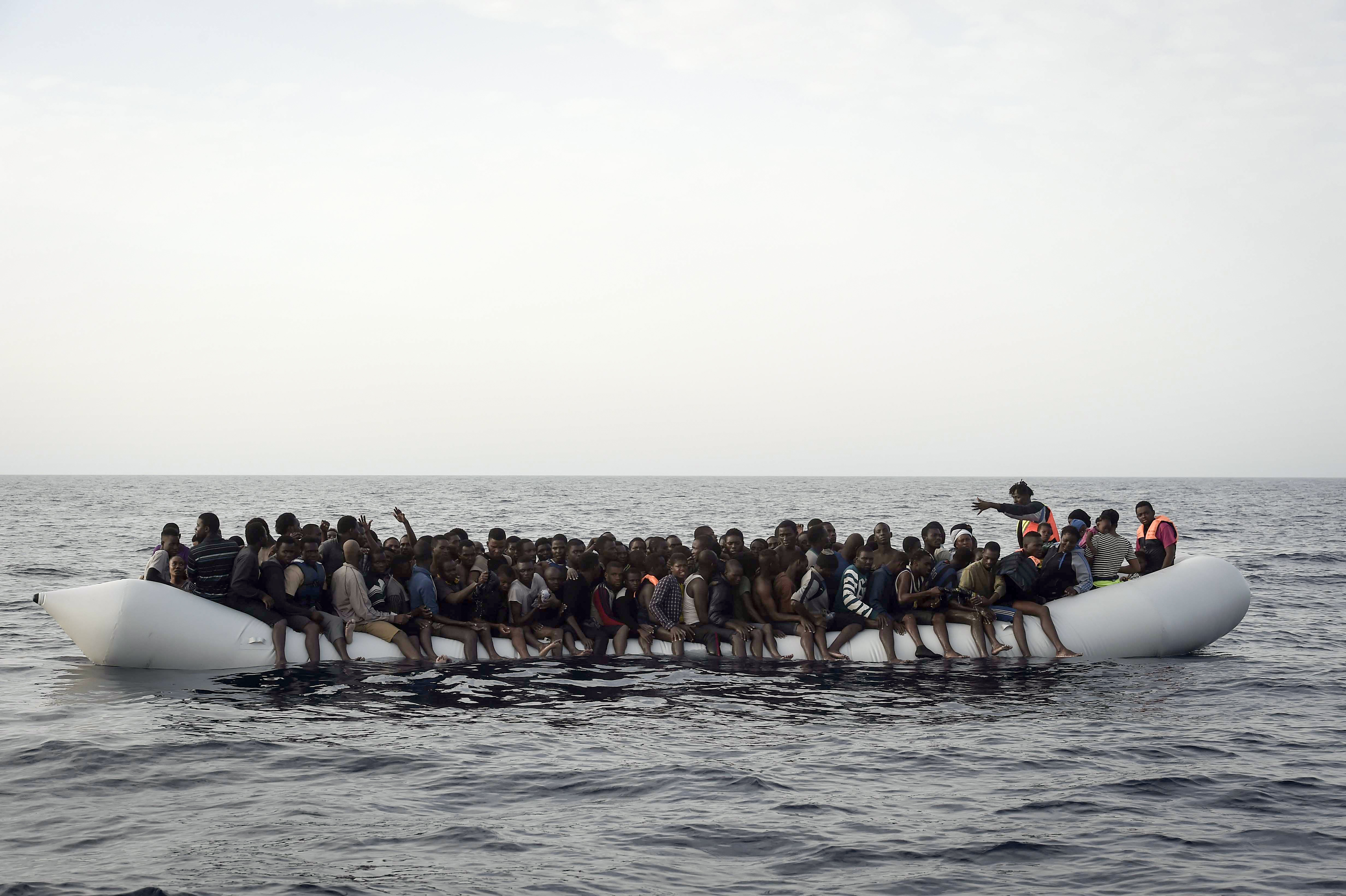Migrants wait to be rescued by members of Proactiva Open Arms NGO in the Mediterranean Sea, some 12 nautical miles north of Libya, on October 4, 2016. At least 1,800 migrants were rescued off the Libyan coast, the Italian coastguard announced, adding that similar operations were underway around 15 other overloaded vessels. / AFP PHOTO / ARIS MESSINIS