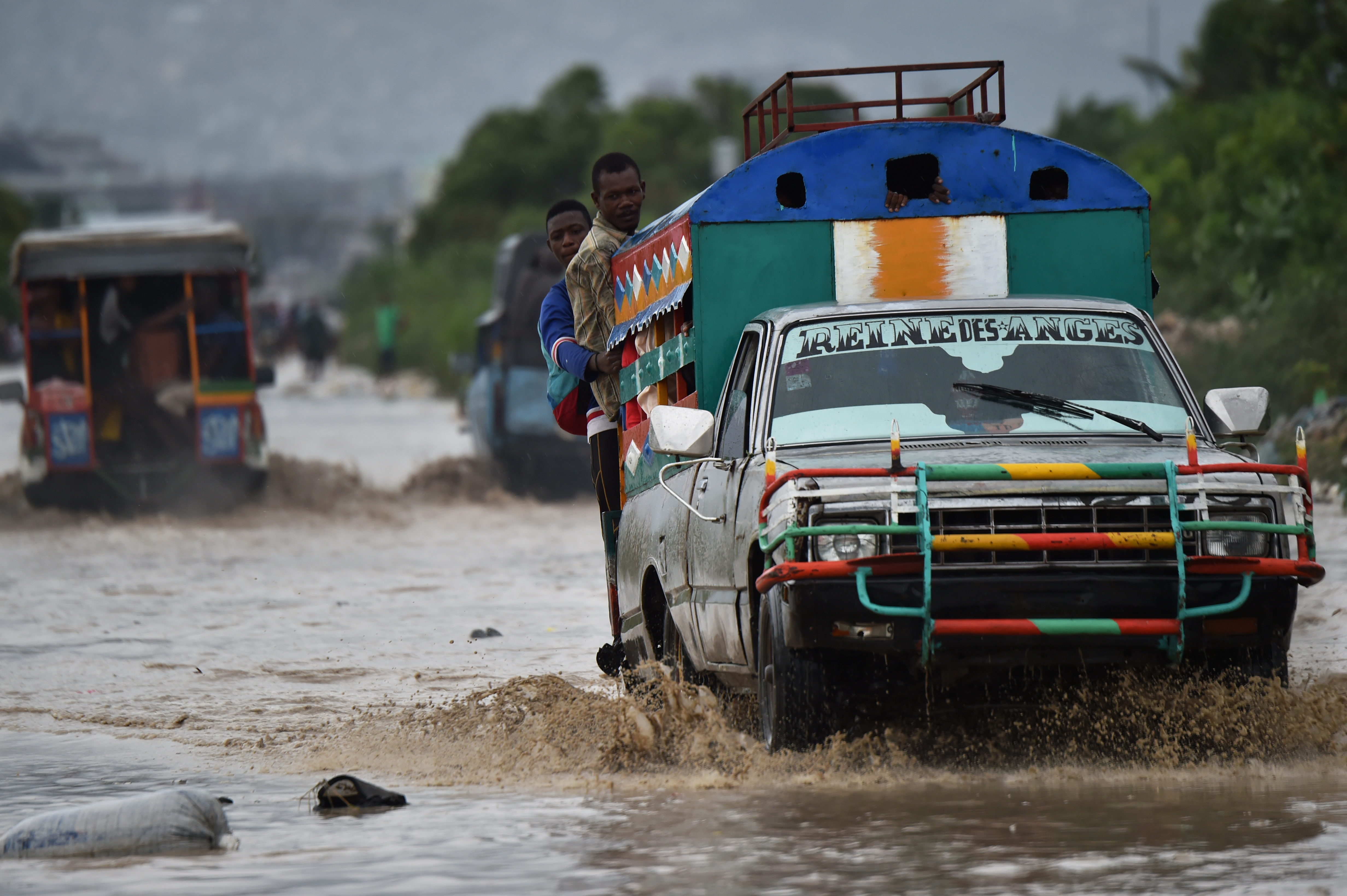 A car makes its way through a flooded street, in a neighbourhood of the commune of Cite Soleil, in the Haitian Capital Port-au-Prince, on October 4, 2016. Hurricane Matthew slammed into Haiti, triggering floods and forcing thousands to flee the path of a storm that has already claimed three lives in the poorest country in the Americas. / AFP PHOTO / HECTOR RETAMAL