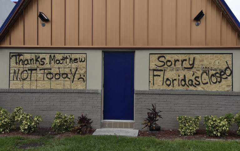A boarded up IHOP restaurant has messages to Hurricane Matthew written on the plywood as it sits closed ahead of Hurricane Matthew on Cocoa Beach, Florida on October 5, 2016. Hurricane Matthew, the Caribbean's worst storm in nearly a decade, barreled towards the Bahamas Wednesday morning after killing nine people and pummeling Haiti and Cuba. Far to the north, the first evacuations were ordered in the United States as coastal residents prepared to escape the approaching monster storm, expected off the East Coast later this week.  / AFP PHOTO / RHONA WISE