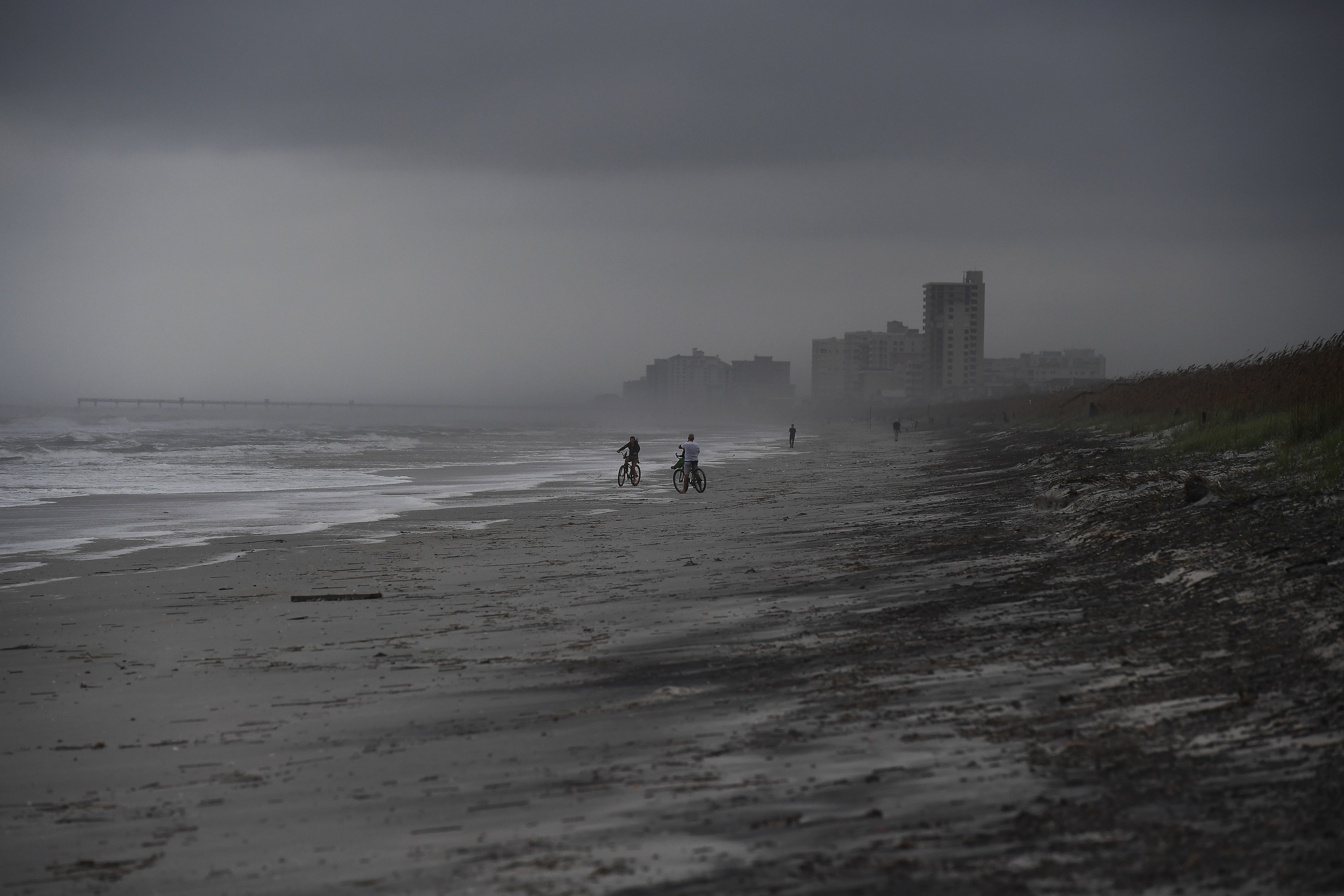 People bike on the beach ahead of hurricane Matthew in Atlantic Beach, Florida, on October 5, 2016. The United States began evacuating coastal areas as Hurricane Matthew churned toward the Bahamas, after killing at least nine people in the Caribbean in a maelstrom of wind, mud and water. / AFP PHOTO / Jewel SAMAD