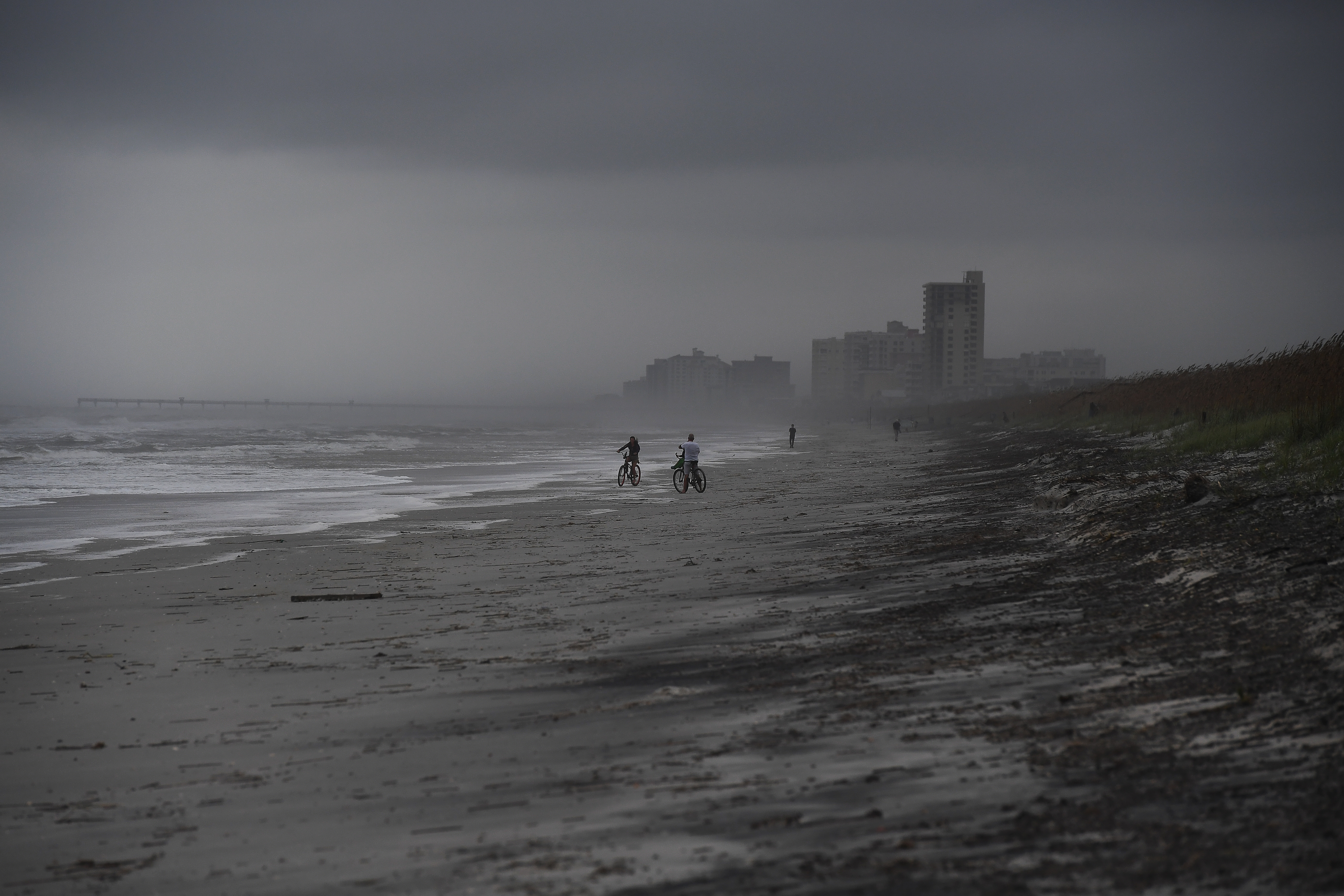 People bike on the beach ahead of hurricane Matthew in Atlantic Beach, Florida, on October 5, 2016. The United States began evacuating coastal areas  as Hurricane Matthew churned toward the Bahamas, after killing at least nine people in the Caribbean in a maelstrom of wind, mud and water. / AFP PHOTO / Jewel SAMAD